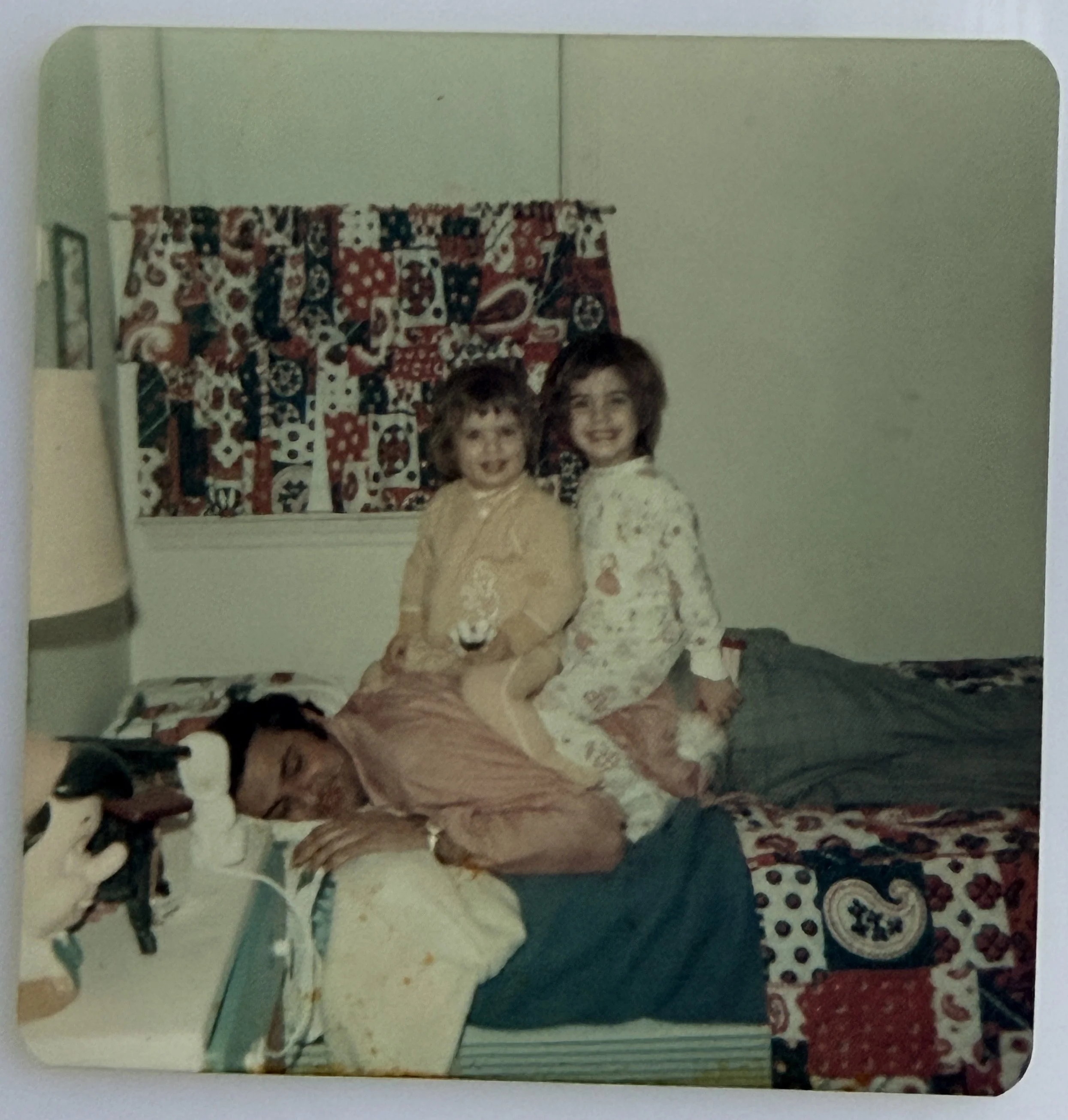 sisters wearing sleepers playing giddyup on tired dad's back.