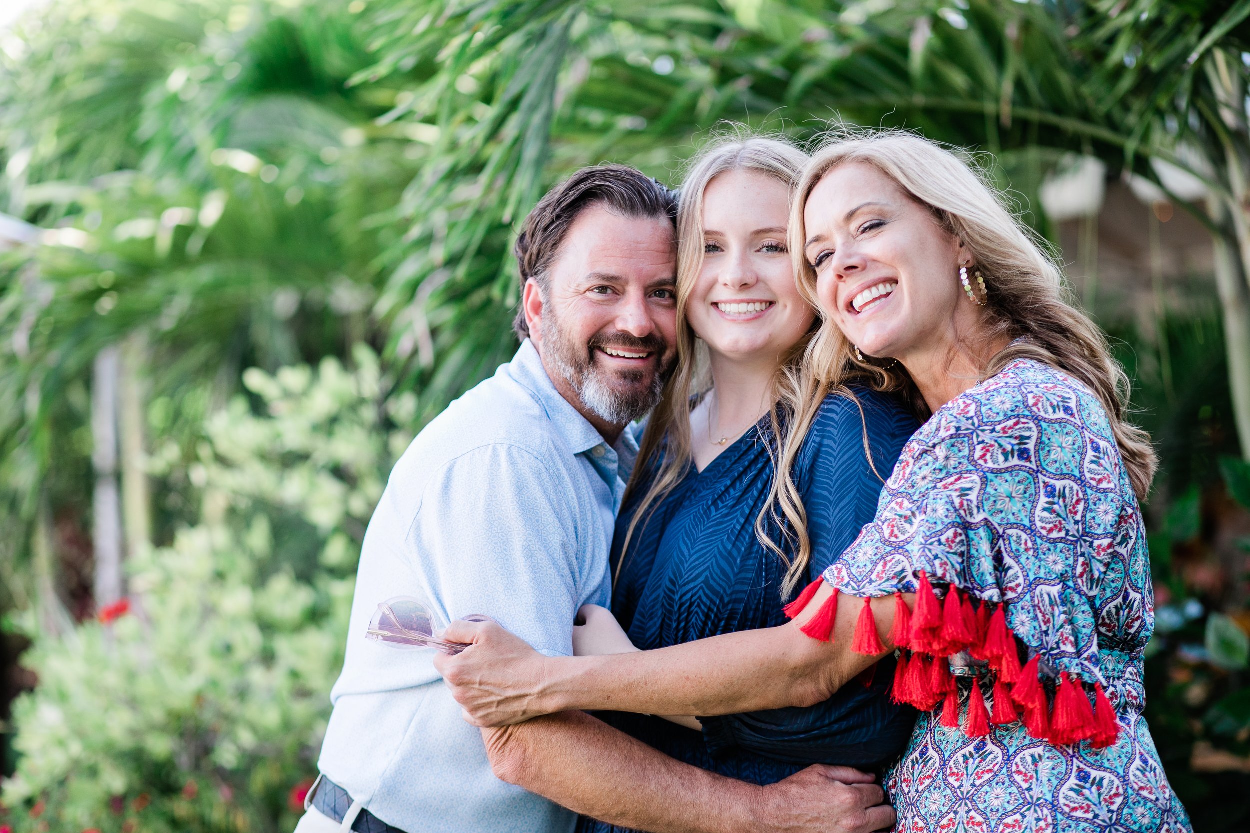 father and mother hug high school graduate daughter