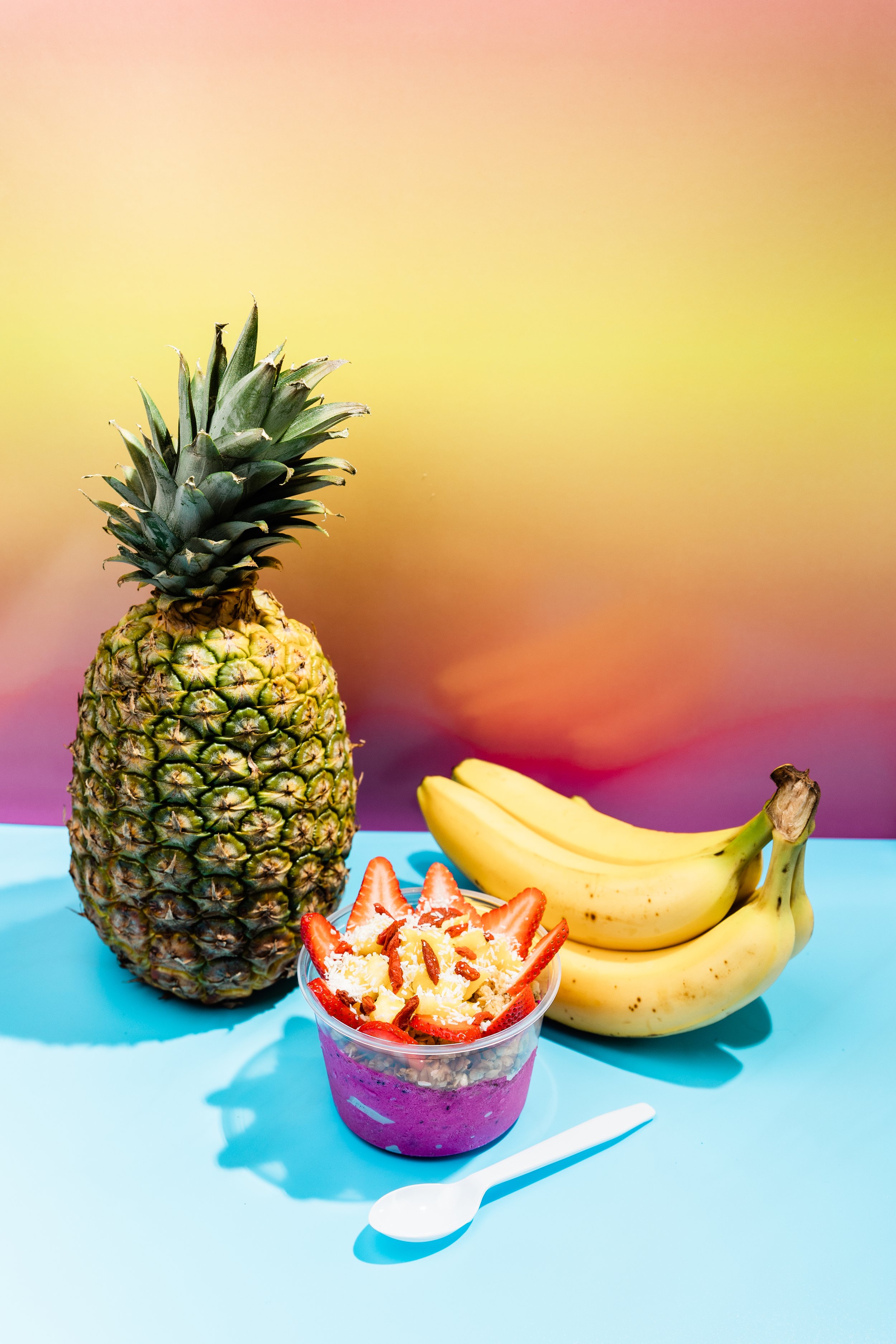 pineapple, bananas, and Fit Bowl acai bowl against sunset background