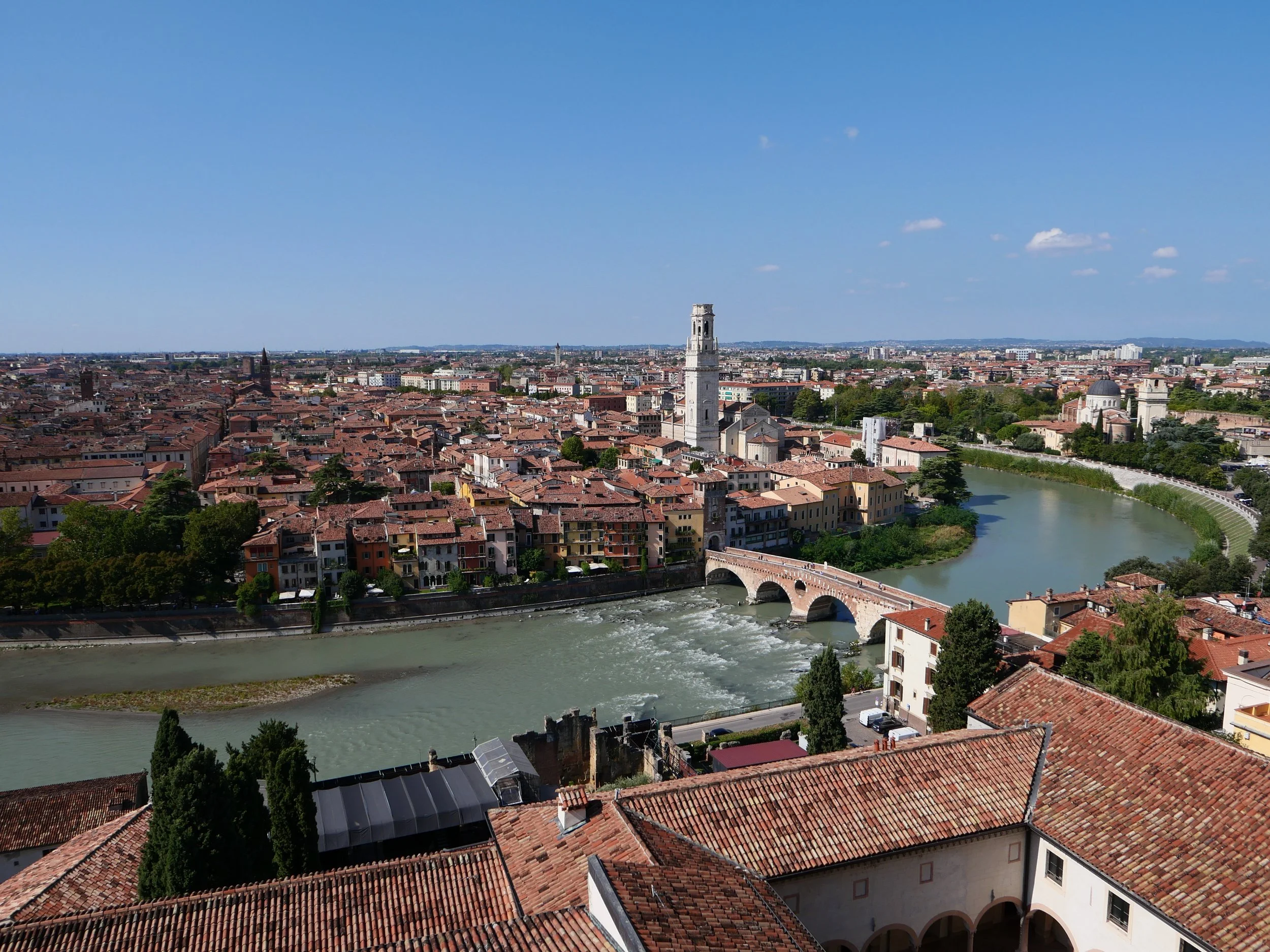 overview of the red tile roofs of Verona, Italy with curving river and tall white tower