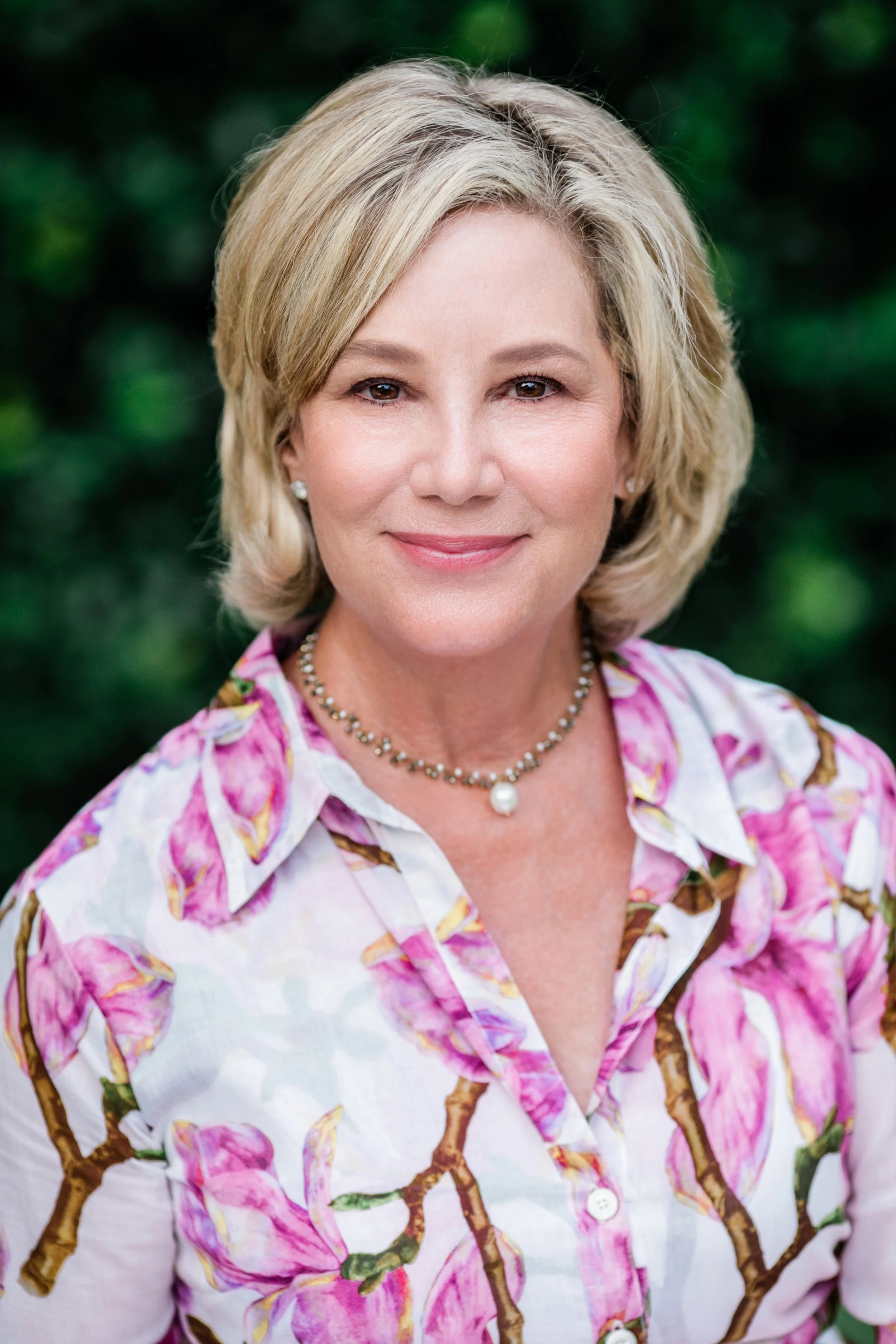 environmental portrait of a woman with blond hair and wearing a dress with pink flowers