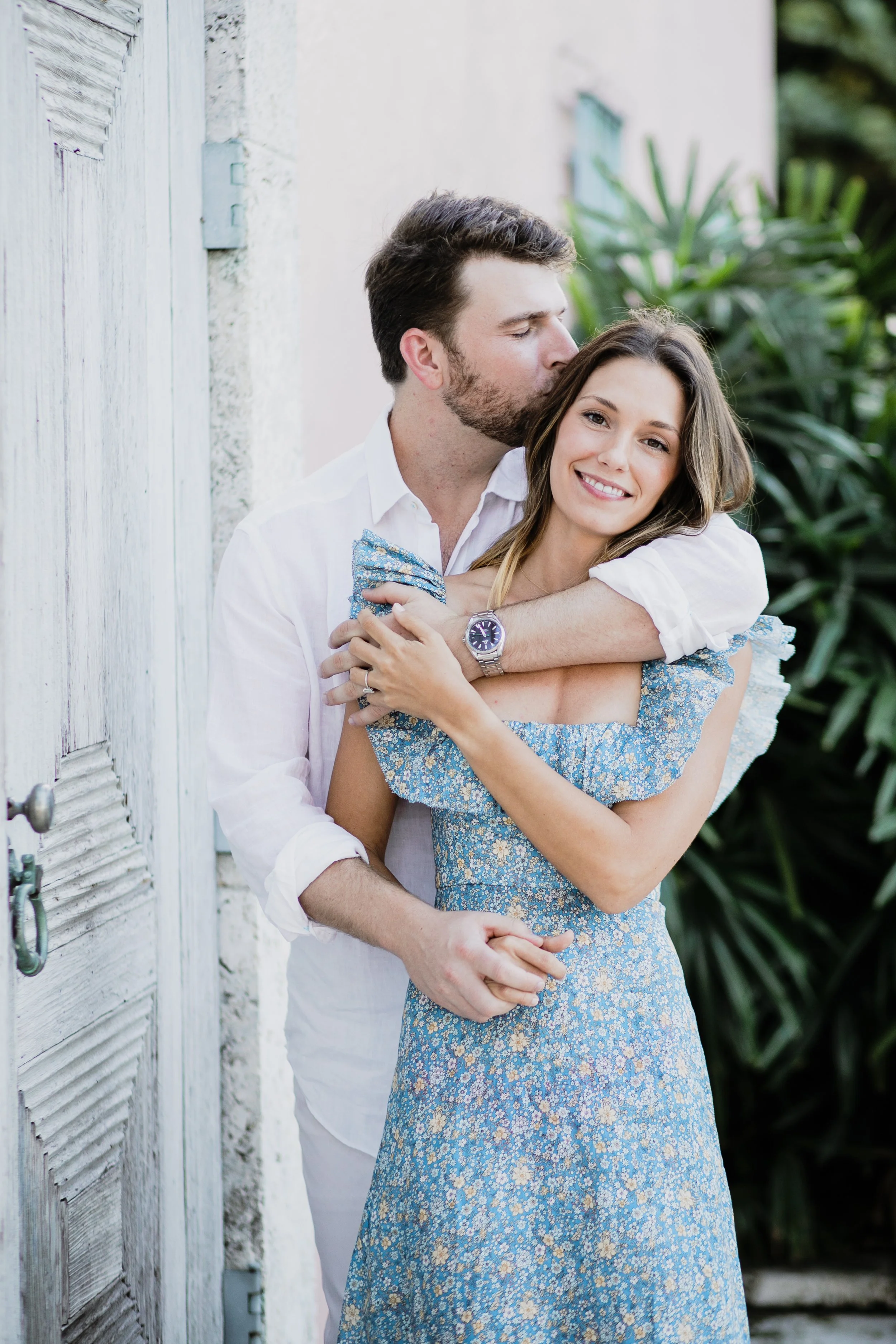 Man kisses woman on the head while wrapping her in his arms during an engagement session in Boca Grande
