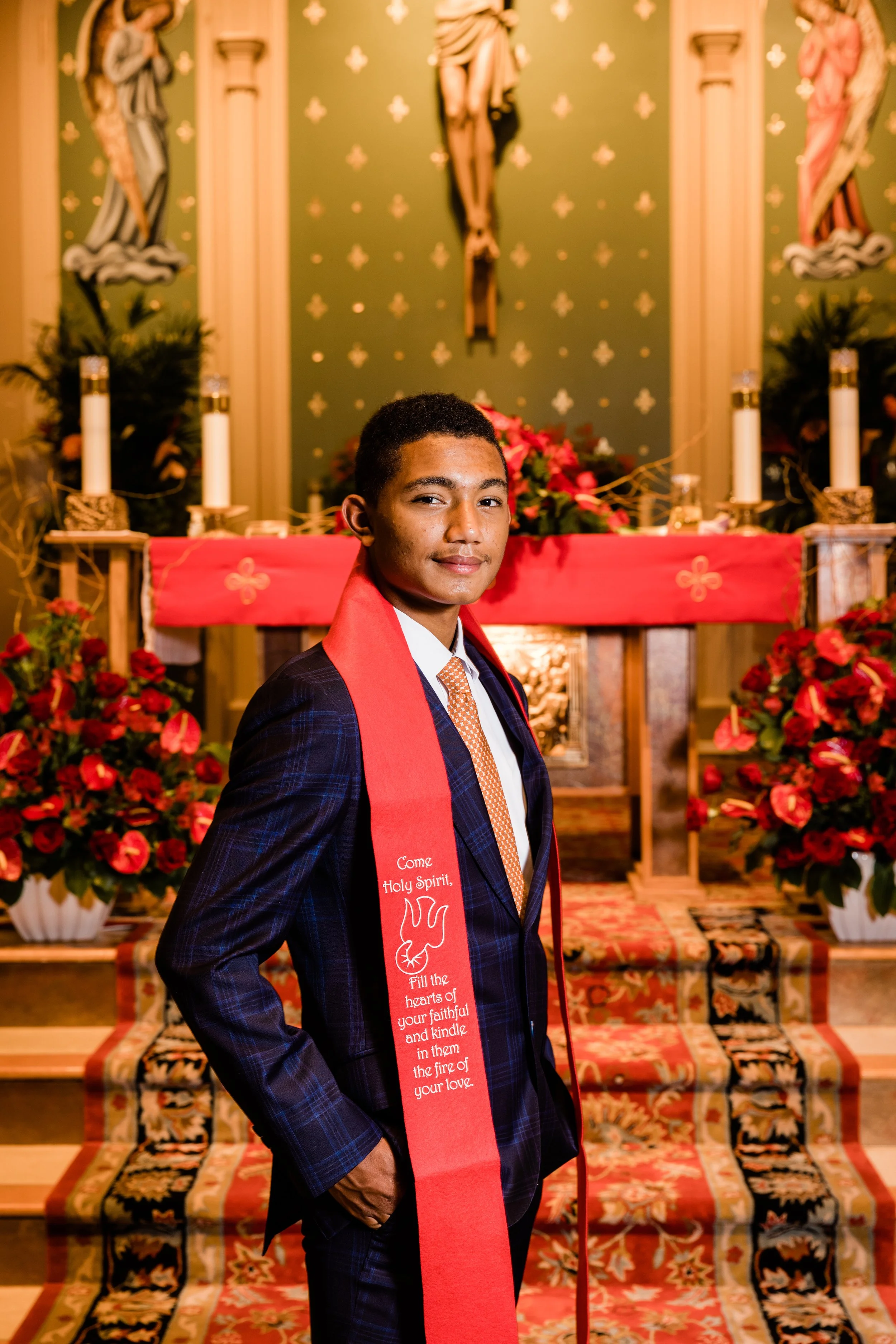 Boy in a dark suit with a red scarf draped around his shoulders on the alter in a church