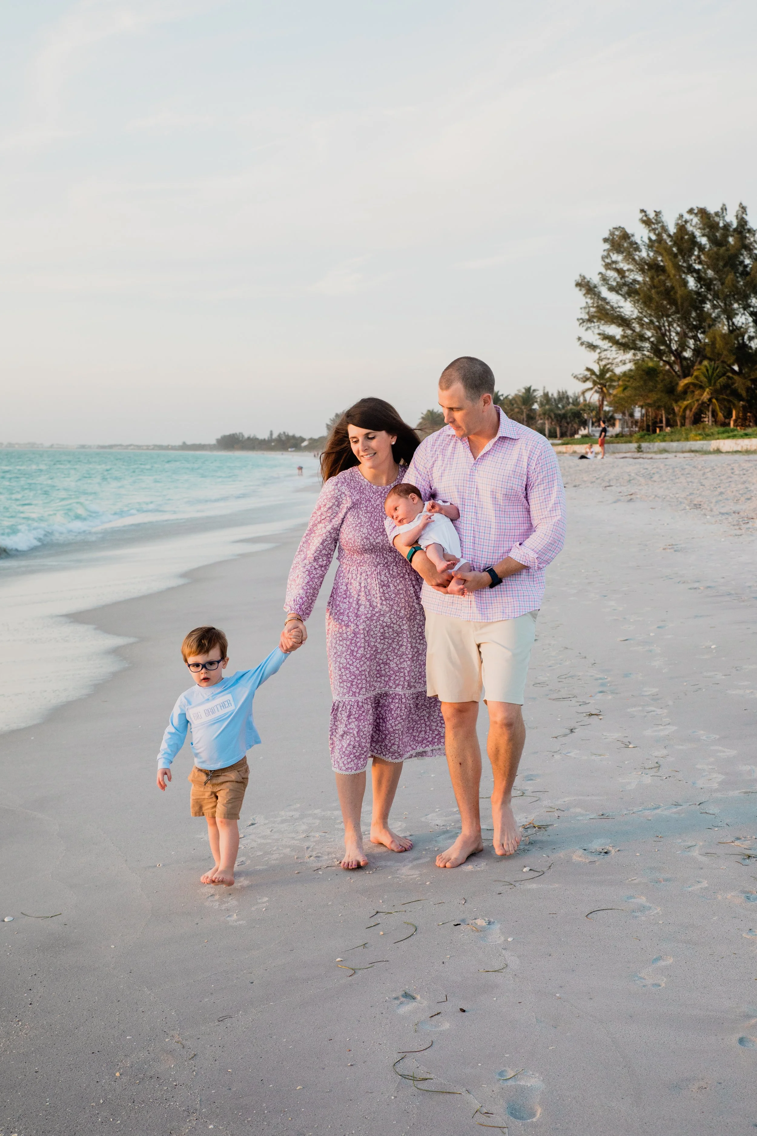family of four, including a newborn baby, walks on the beach in Boca Grande for a family portrait session