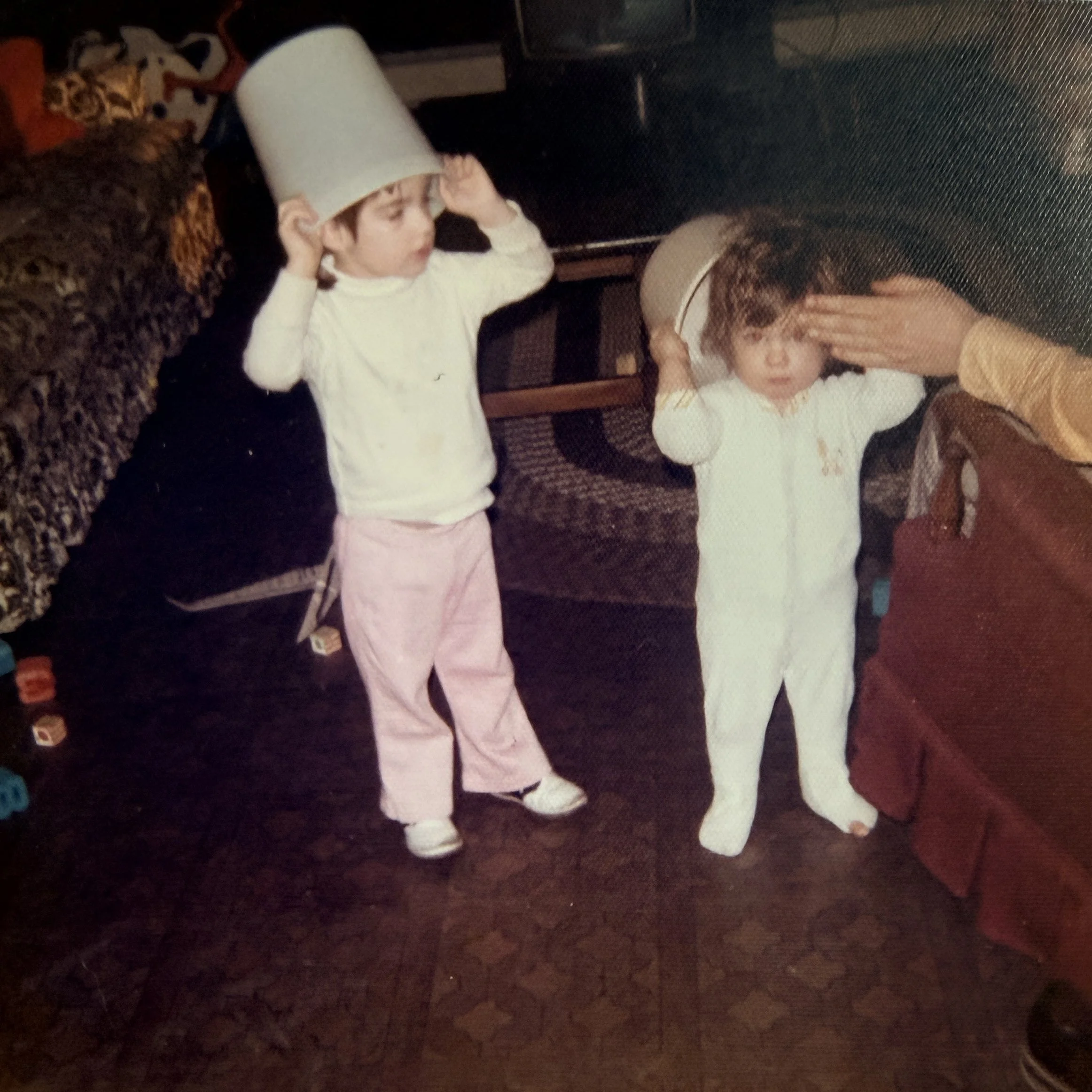 two kids holding buckets in the family room of a 1970s home