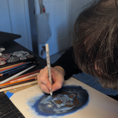 Person drawing or coloring a tiger on paper with colored pencils or markers.
