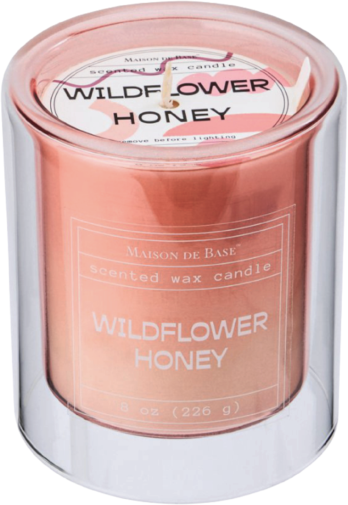 A pink scented wax candle labeled 'Wildflower Honey' by Maison de Base in a glass jar.