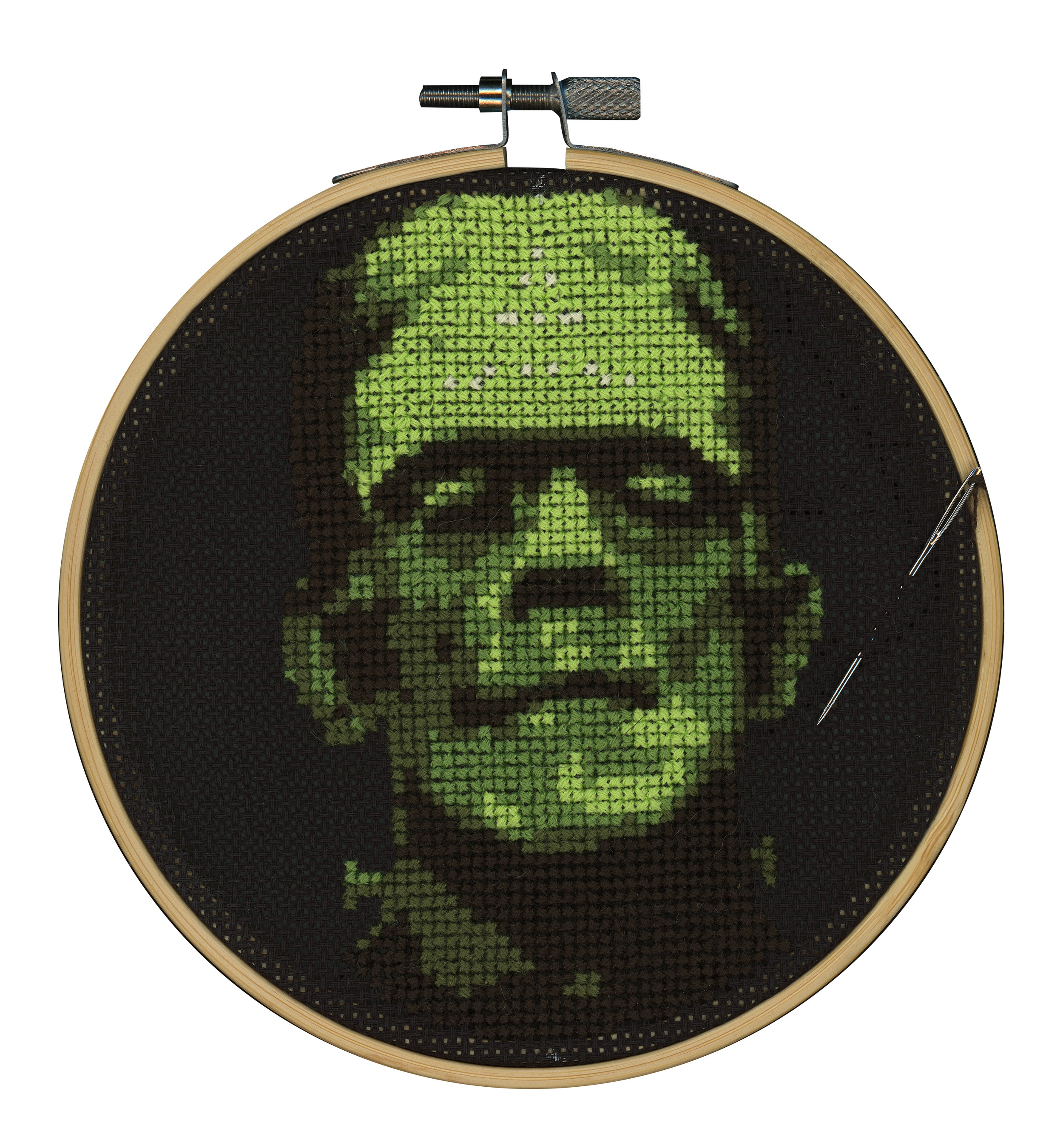 Cross-stitch artwork of a man's face with glasses, a beard, and a beanie hat in shades of green on black fabric.