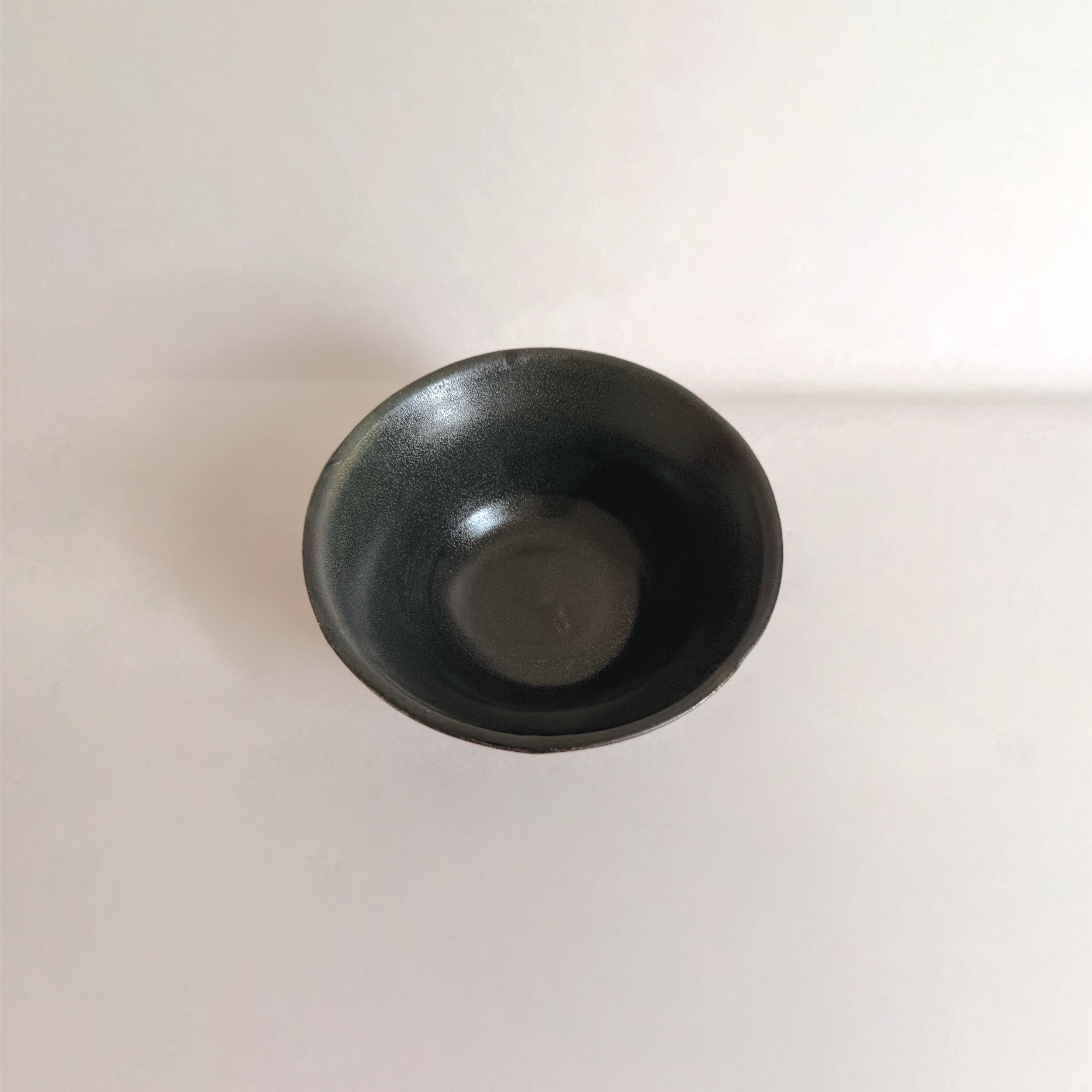 A top-down view of a black cup on a white surface.