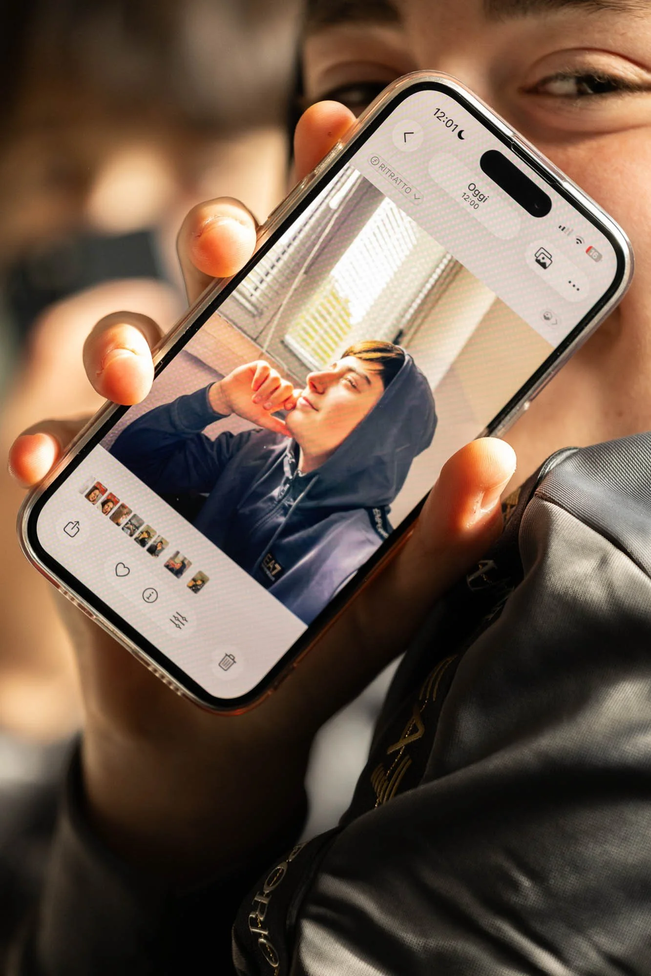 Persona che tiene uno smartphone con in primo piano una foto di un giovane ragazzo sorridente.