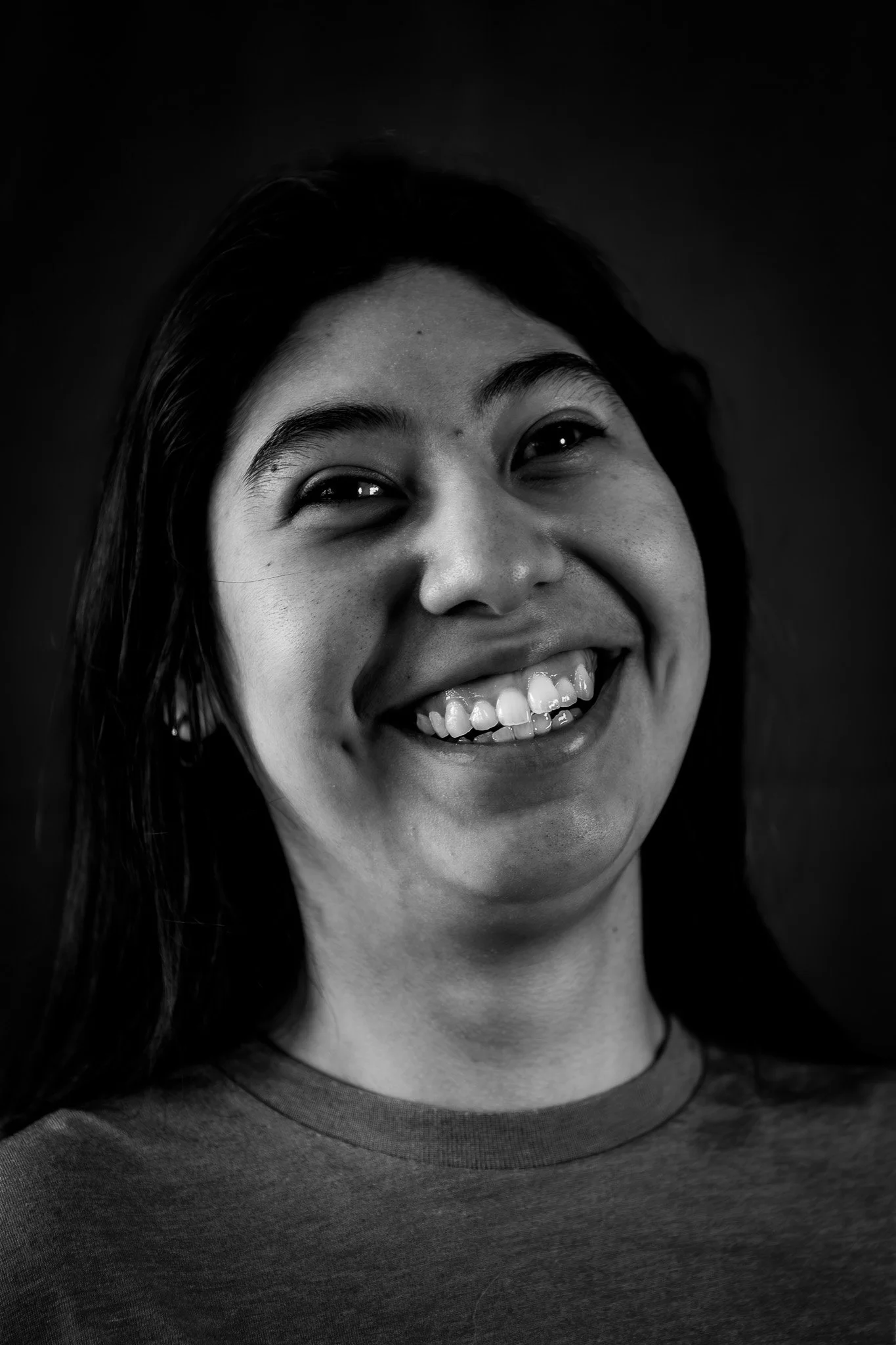 Ritratto di una donna sorridente in bianco e nero, con capelli scuri e pelle chiara, che indossa una maglietta casual.