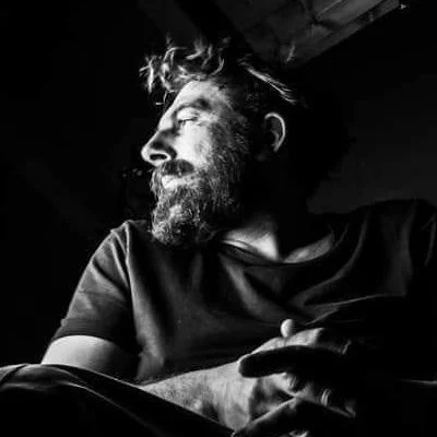 Uomo con barba e capelli lunghi, in profilo, in un'immagine in bianco e nero.
