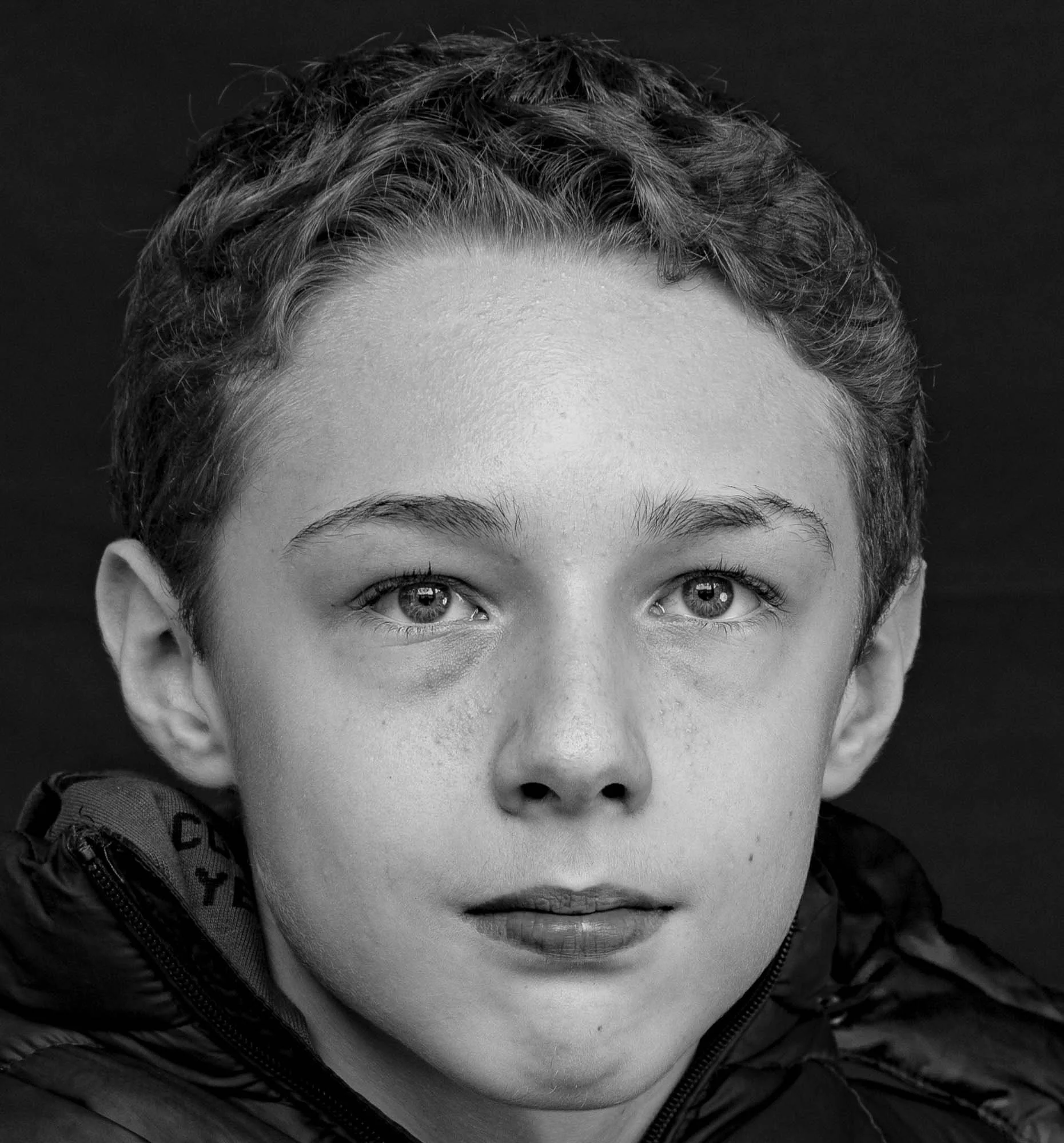 Ritratto in bianco e nero di un bambino con capelli corti ricci e occhi chiari, vestito con una giacca. La foto mostra solo il suo viso.