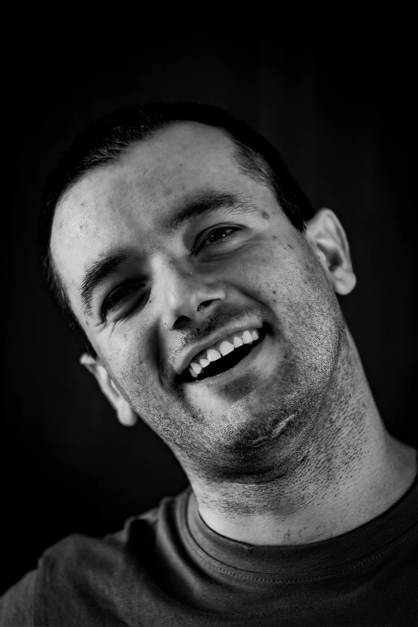 Ritratto di un uomo che sorride, viso parzialmente in ombra, in bianco e nero.