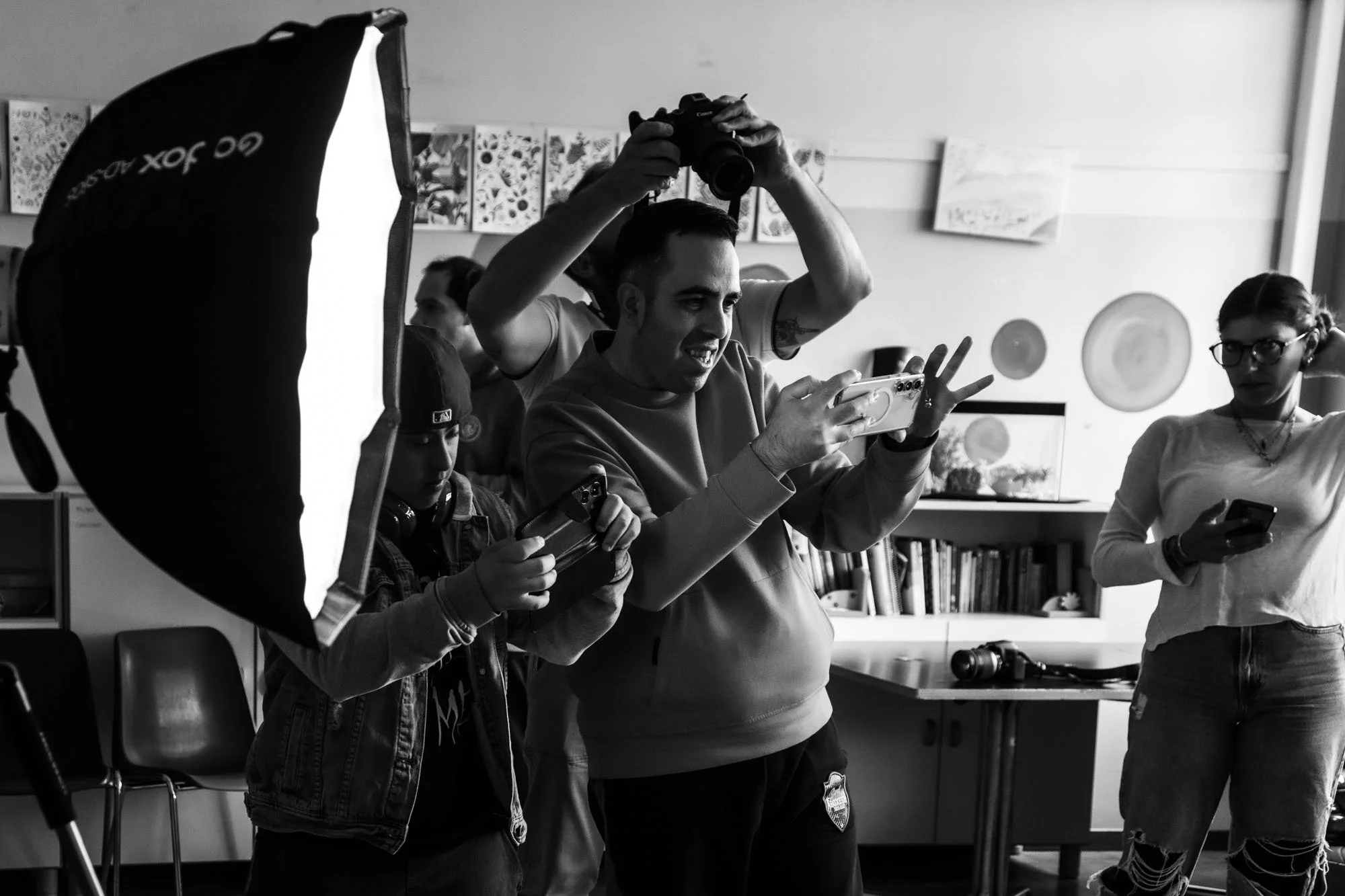 Gruppo di persone che partecipano a una sessione di fotografia in un ambiente interno, con luci e attrezzature fotografiche visibili.