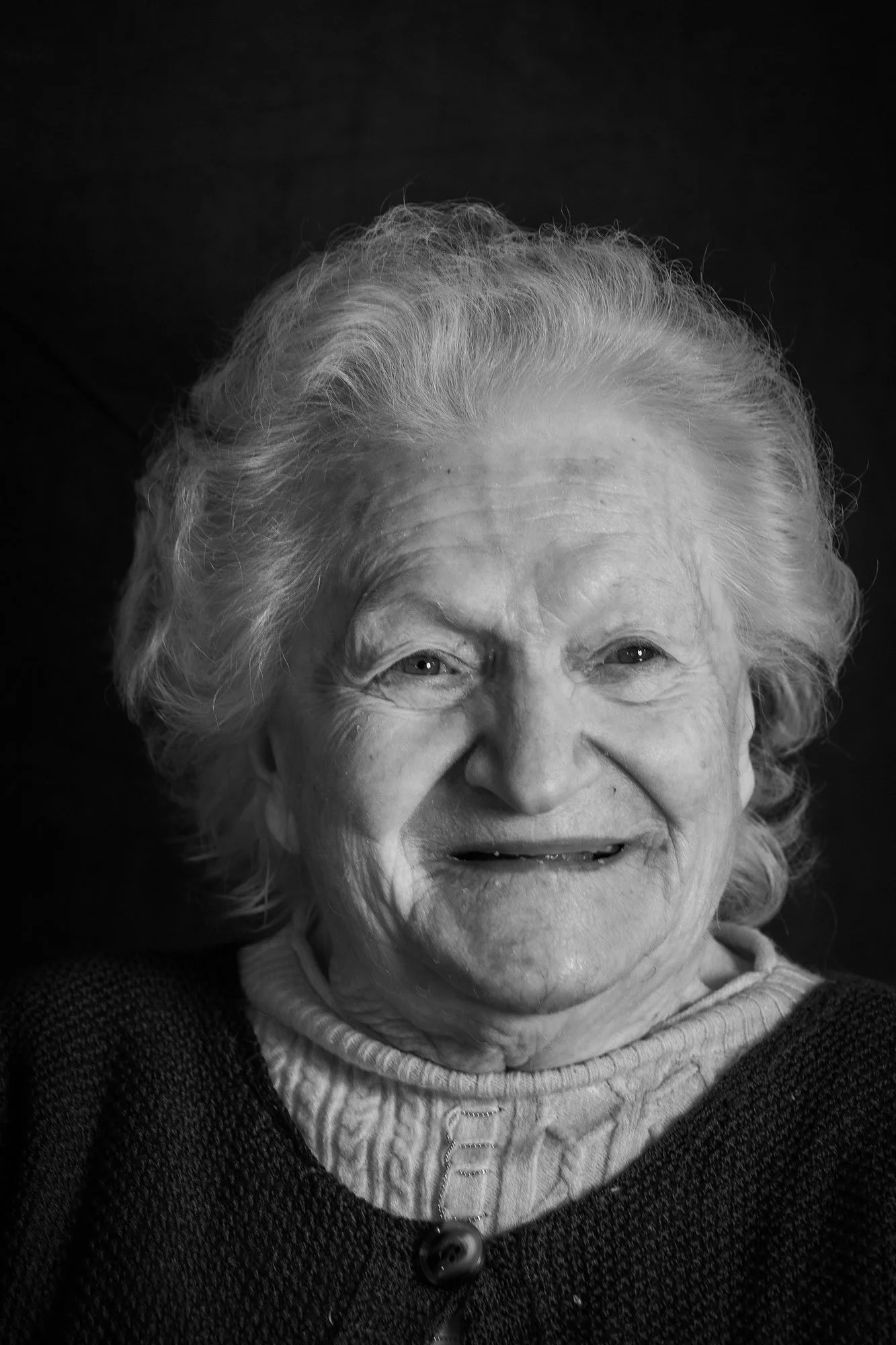 Ritratto di una donna anziana con capelli bianchi, sorridente, in bianco e nero.
