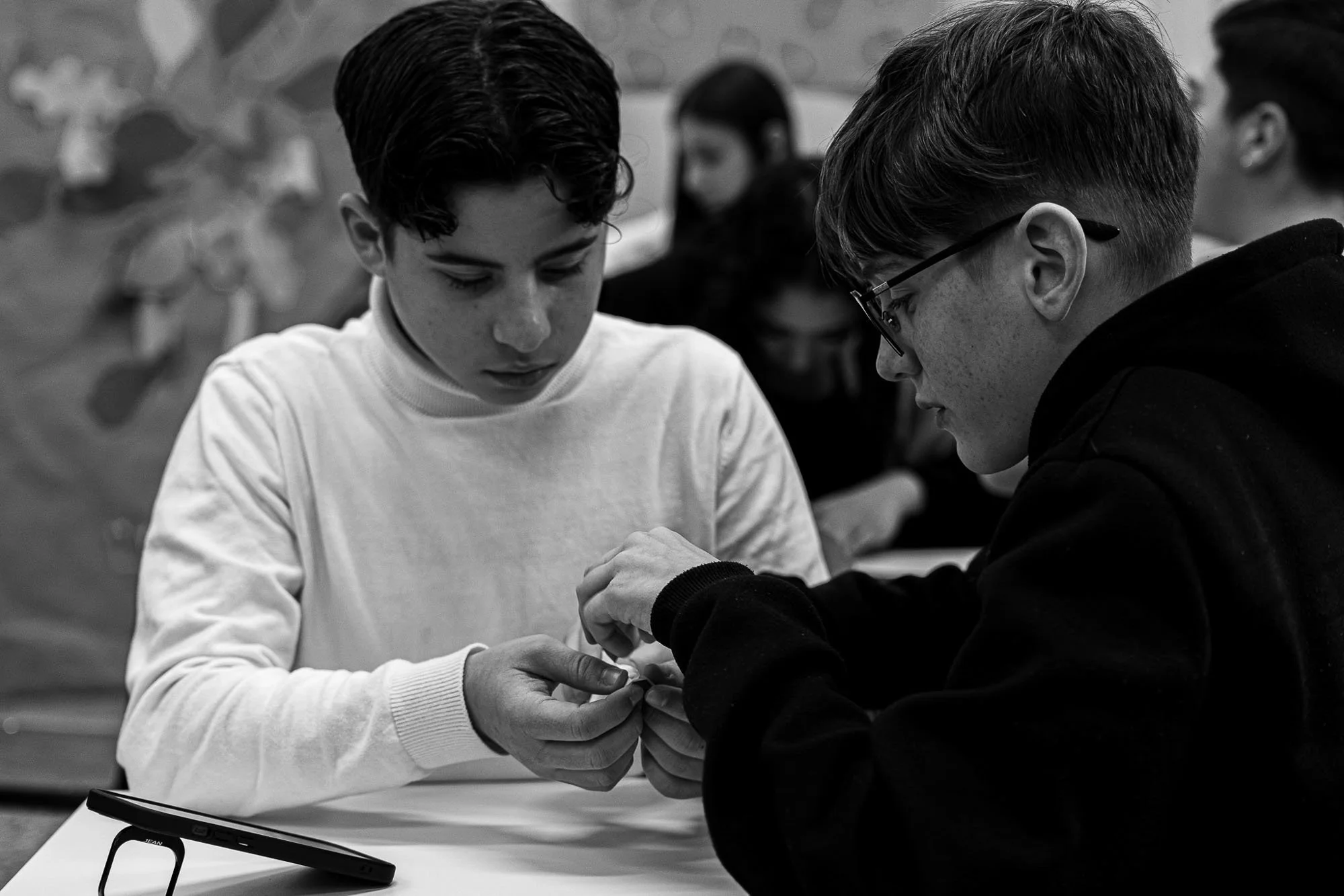 Due giovani stanno costruendo un origami durante una lezione di fotografia in un ambiente scolastico.
