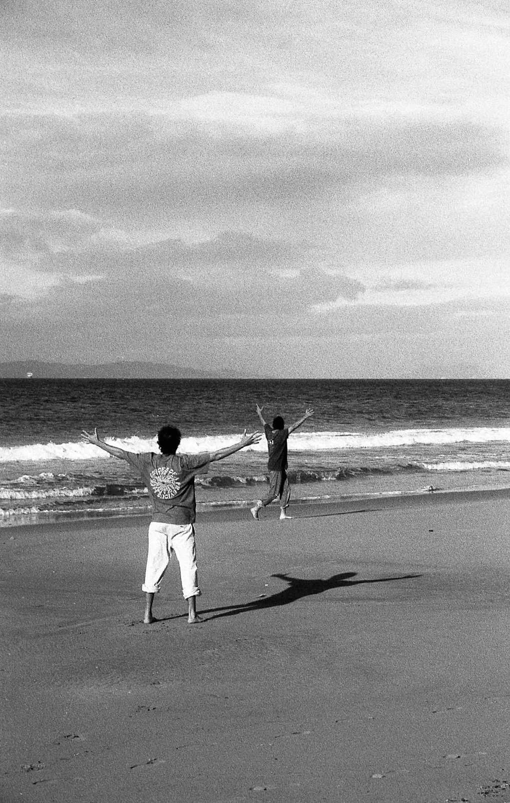 Deux enfants jouent sur la plage, avec la mer en arrière-plan, en noir et blanc.