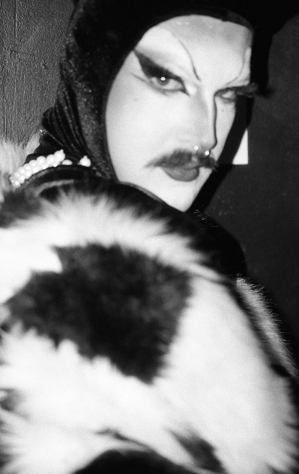 Portrait en noir et blanc d'une personne au maquillage artistique et un visage partiellement visible d'un animal à fourrure.