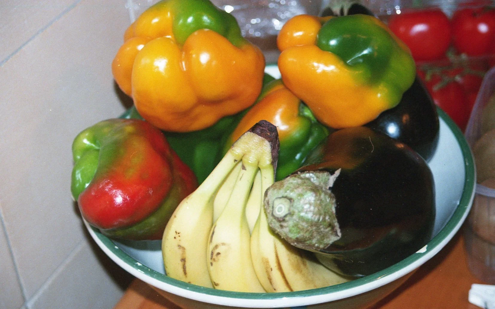 Une assiette contenant des graines de banane, des poivrons multicolores, un avocat mûr, et des tomates rouges.
