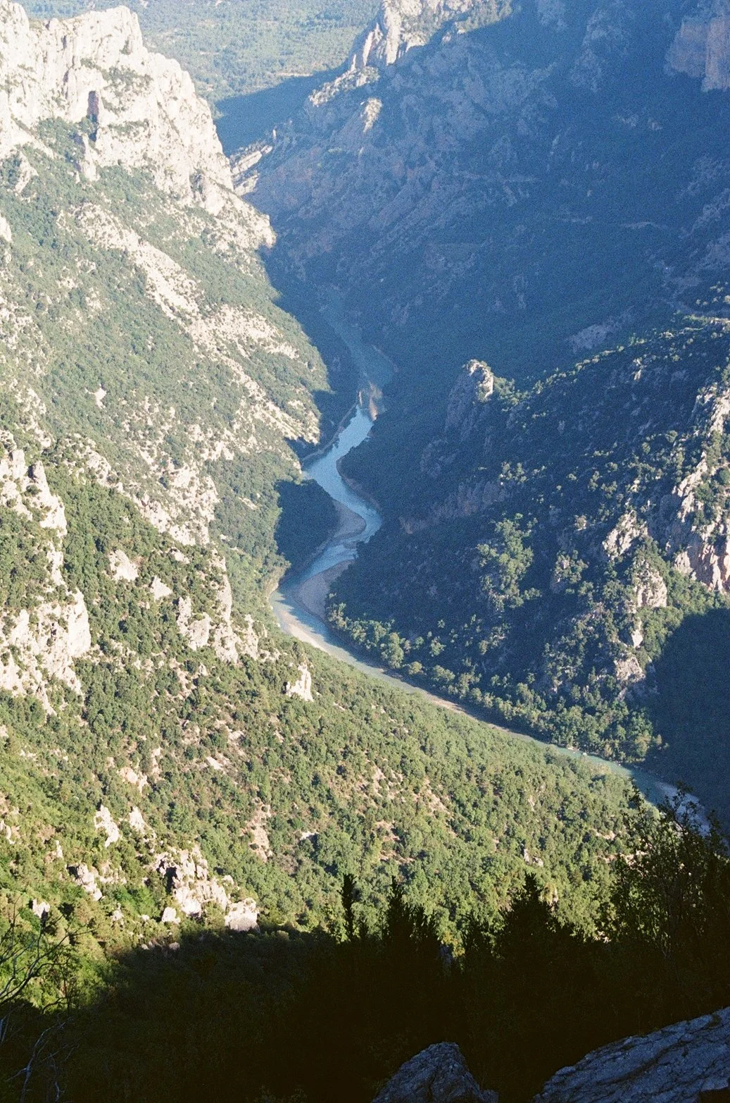 Vue aérienne d'une vallée montagneuse avec une rivière serpentant entre les collines verdoyantes.