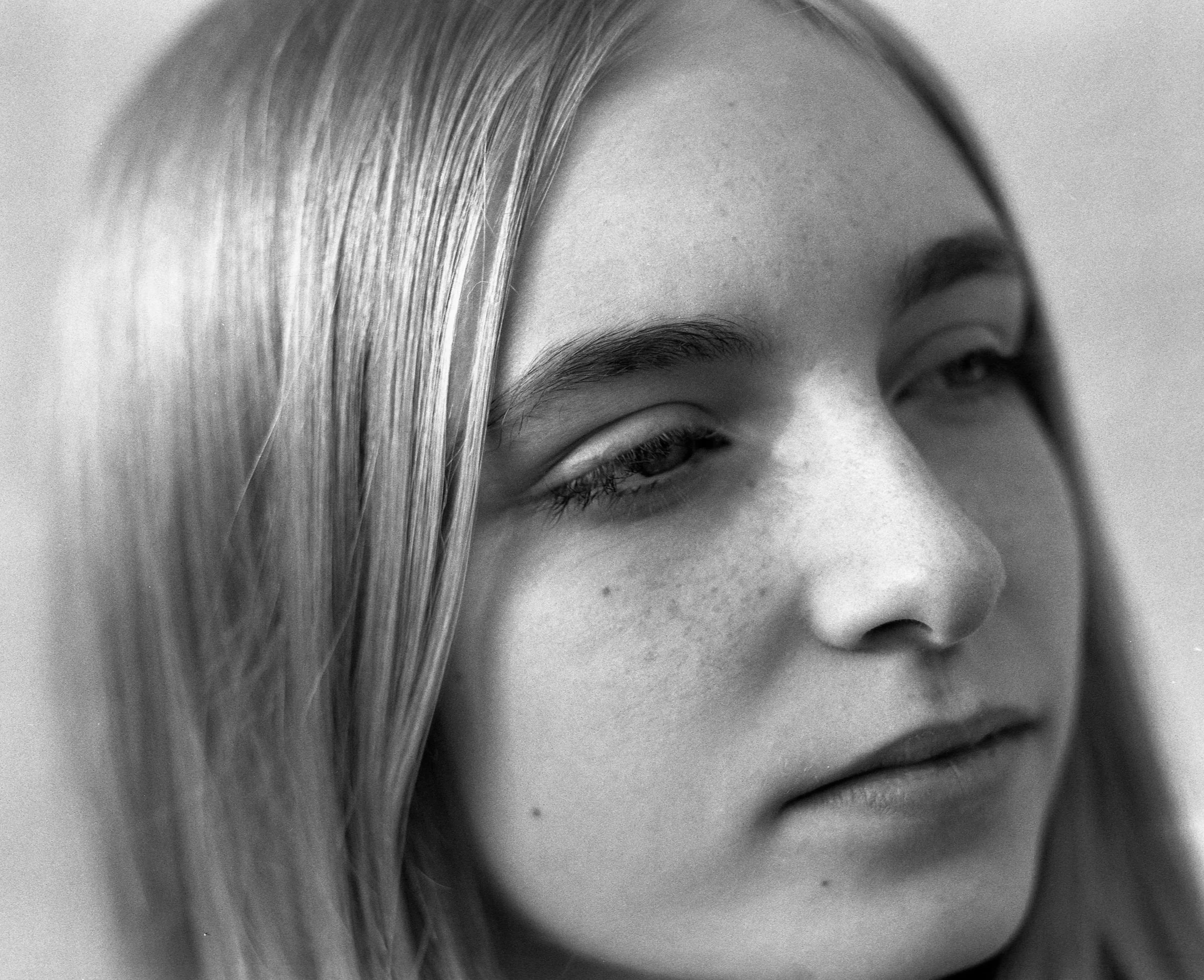 Un portrait en noir et blanc d'une jeune femme avec des cheveux longs et lisses, regardant de côté avec une expression calme.