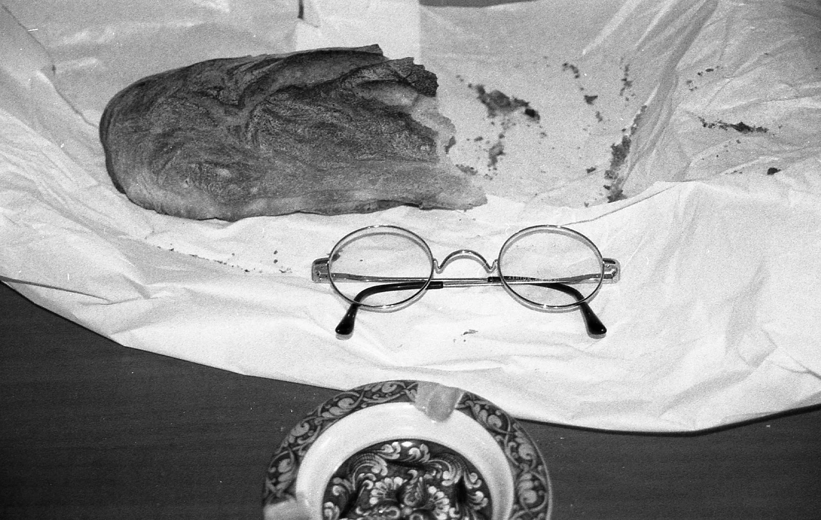 Une pierre sur un papier, une paire de lunettes et un objet circulaire avec un motif floral.