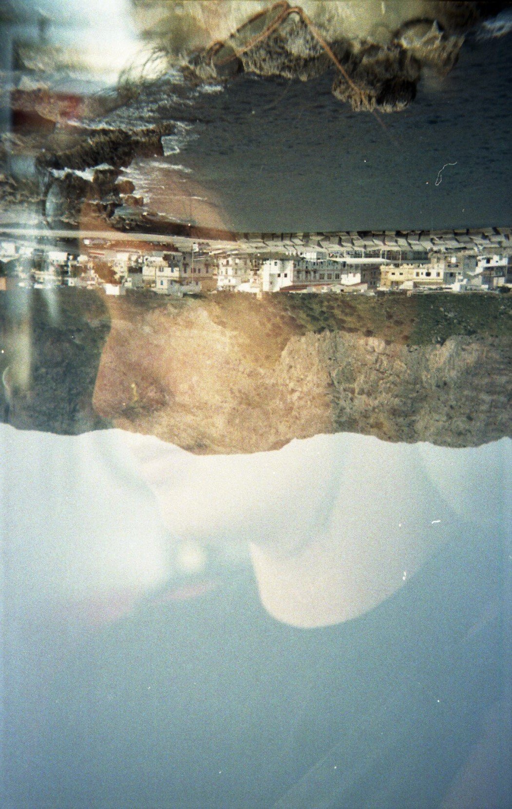 Photo inversée d'une ville côtière et d'une montagne, avec des bâtiments et la mer.