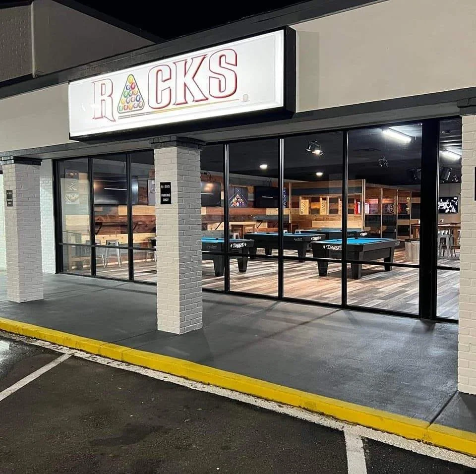 A bar or gaming lounge with large glass windows, a sign reading 'ROCKS' with a pool ball design, and a visible pool table inside.