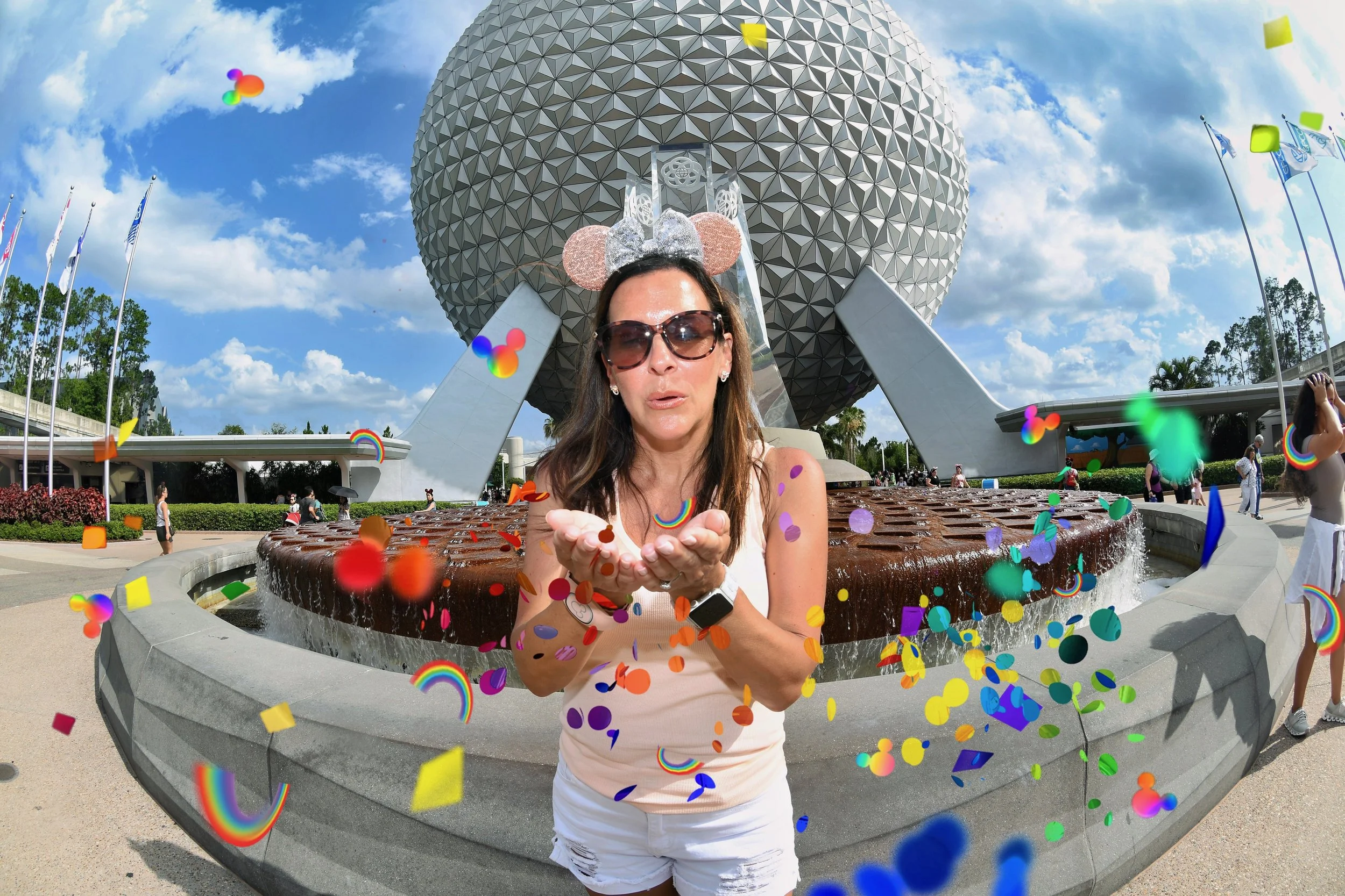 Woman in sunglasses and Minnie Mouse ears blowing confetti at Epcot theme park in Disney World, with Spaceship Earth icon in the background under a blue sky.
