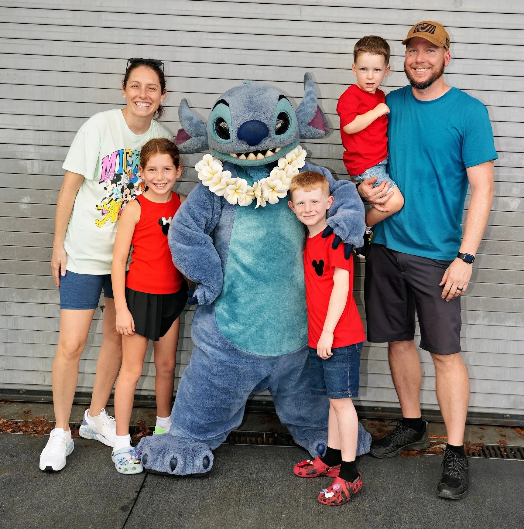 Family posing with Stitch from Disney at a theme park.