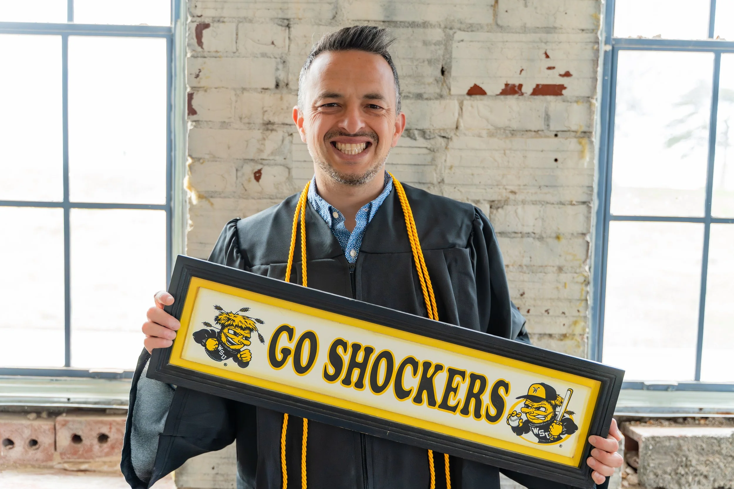 Wichita State University graduate with a Go Shockers sign