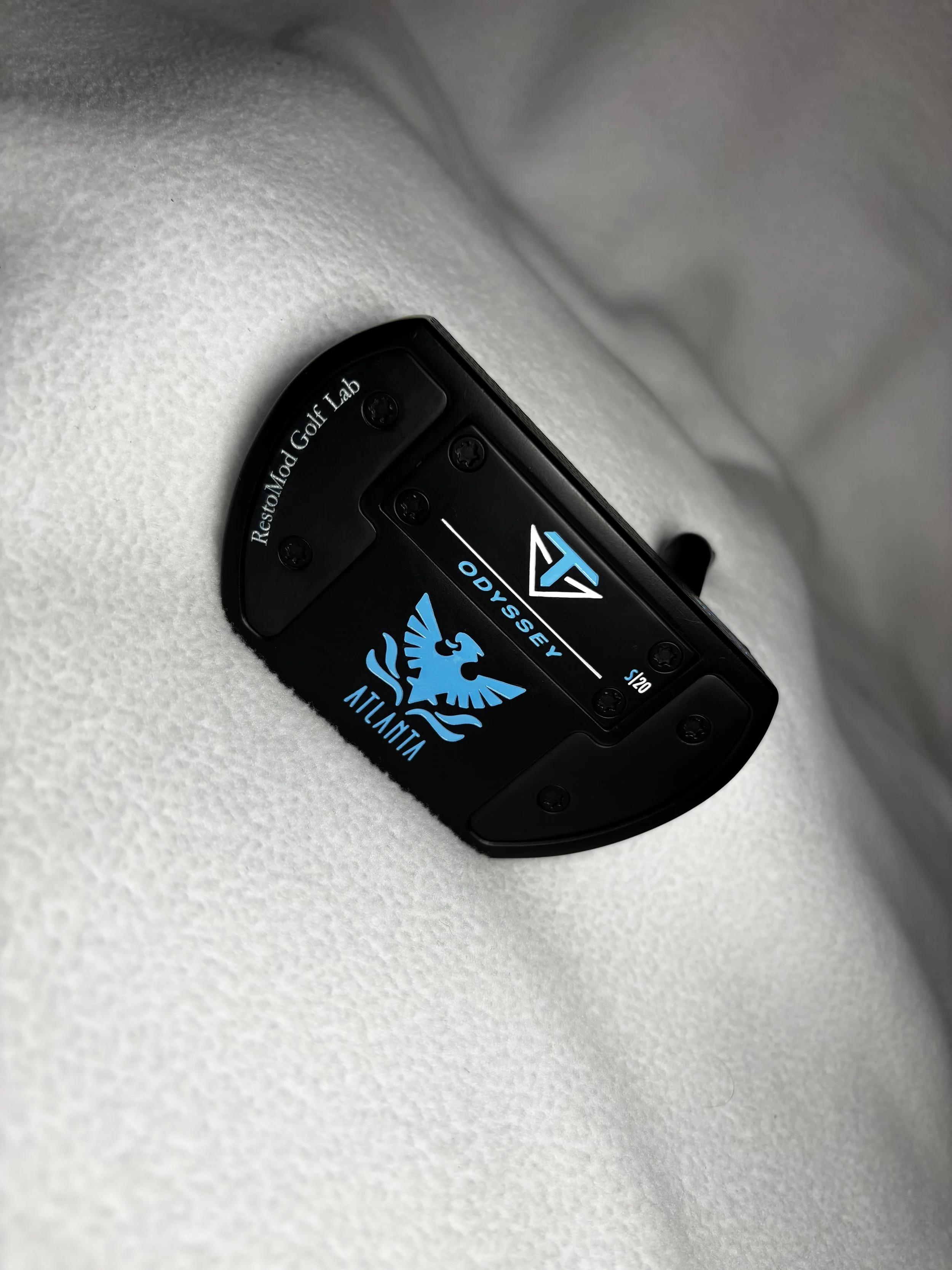 Close-up of a black VersaKyle crash sensor with a blue ATLANTA logo, resting on a white textured surface.