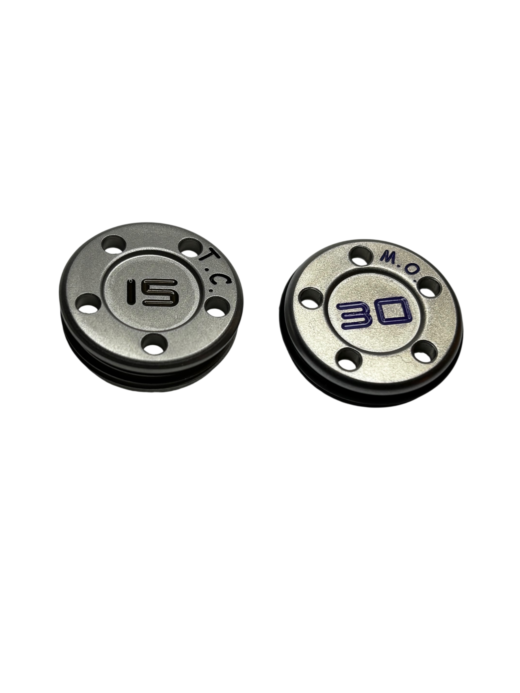 Close-up of two metallic circular objects, possibly buttons or dials, with engraved numbers and markings reading '15' on the left and '30' on the right.