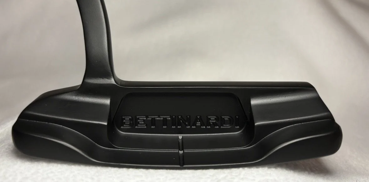 Close-up of a black Bettinardi golf putter with the brand name engraved on the clubhead.