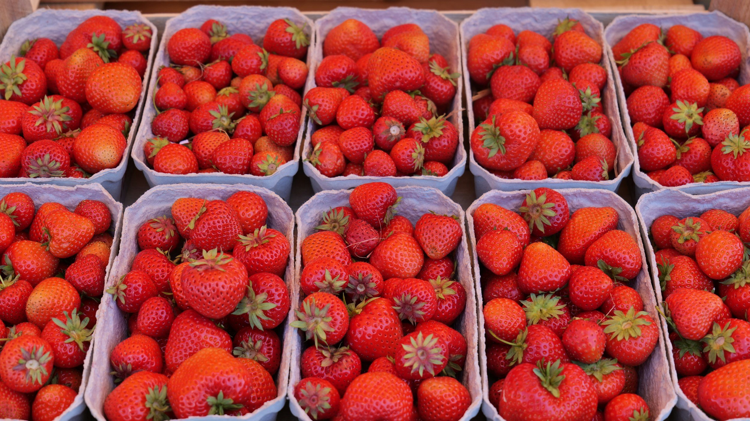 Multiple baskets filled with fresh, ripe strawberries displayed at a market or store.
