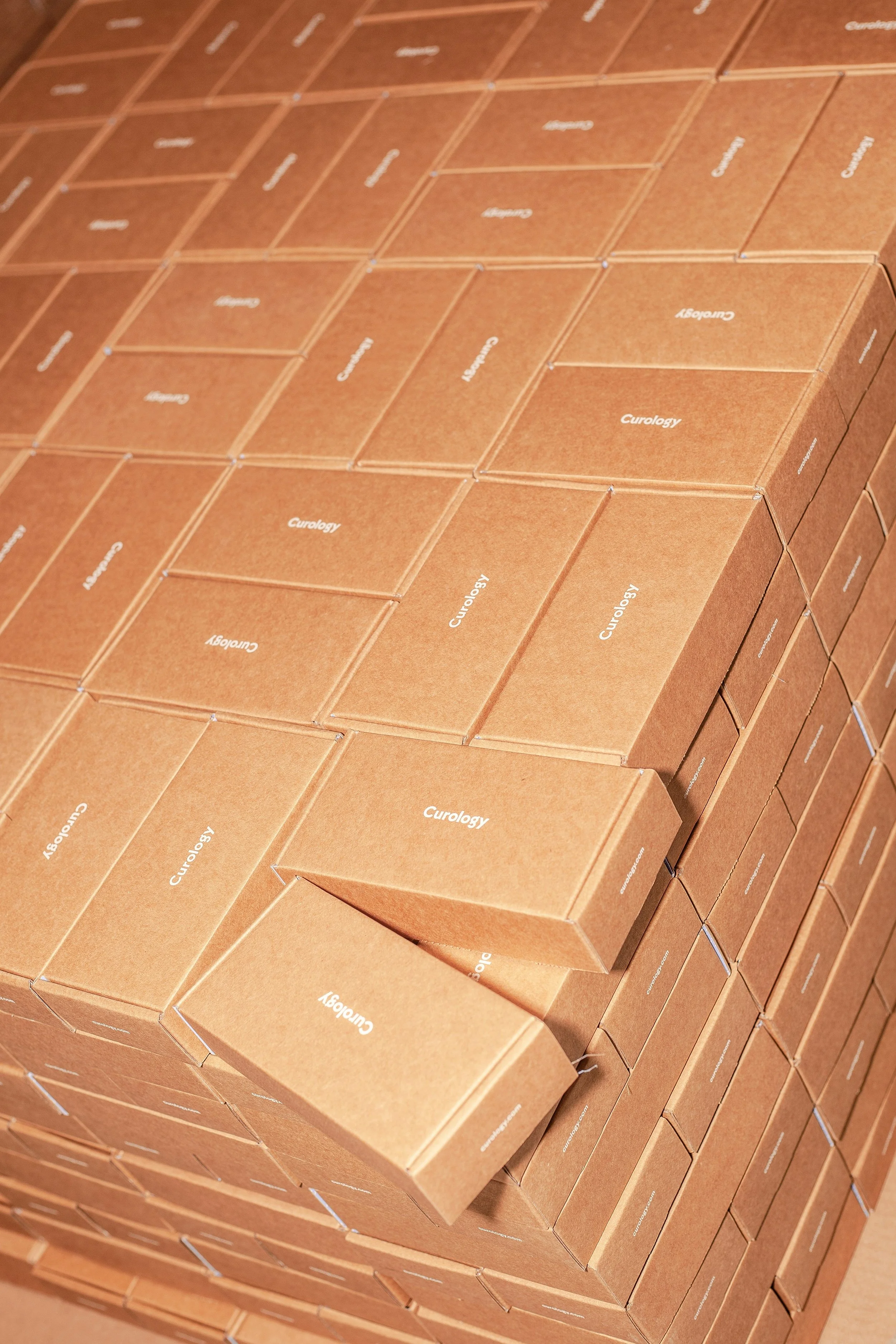 Numerous small brown boxes stacked inside a large open box, each branded in white text.