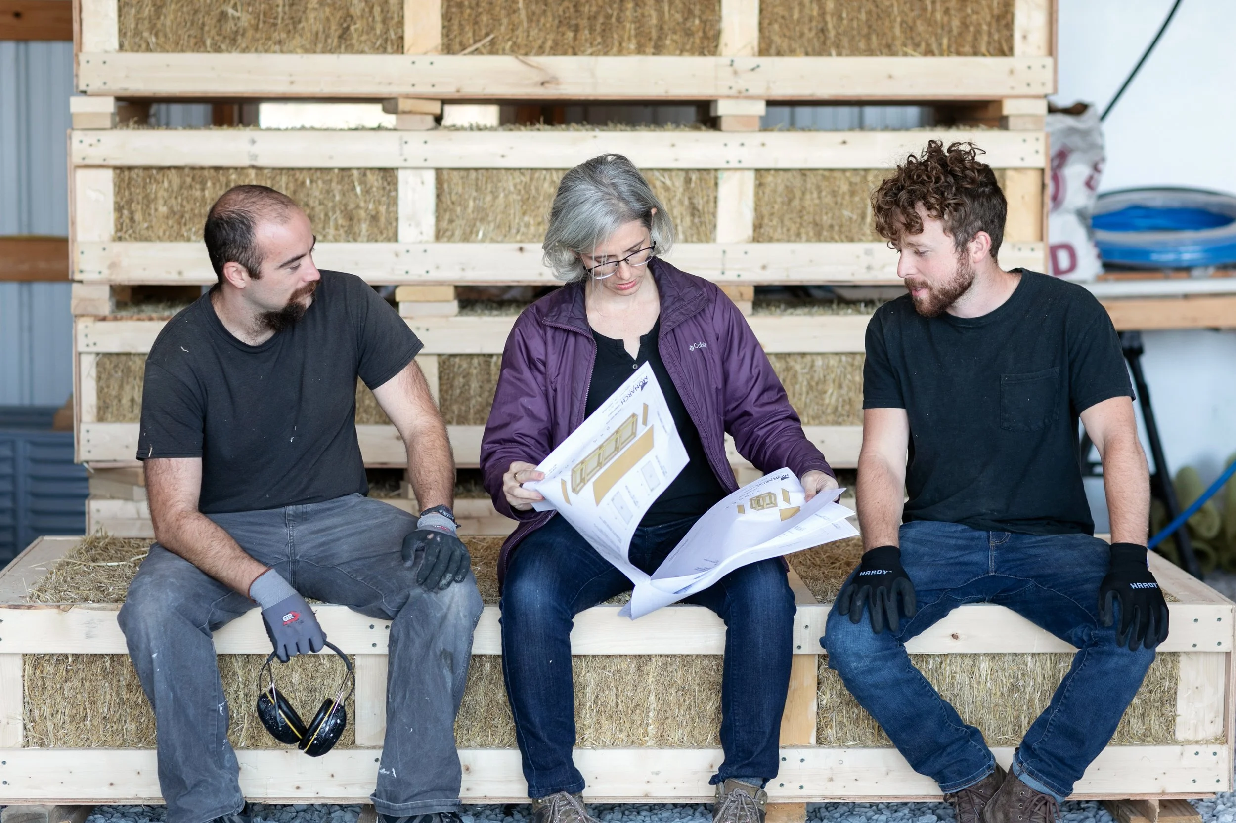 Building Integrity cofounders Tommy, Adrienne, and Virgil reviewing custom prefabricated straw panel design plans together