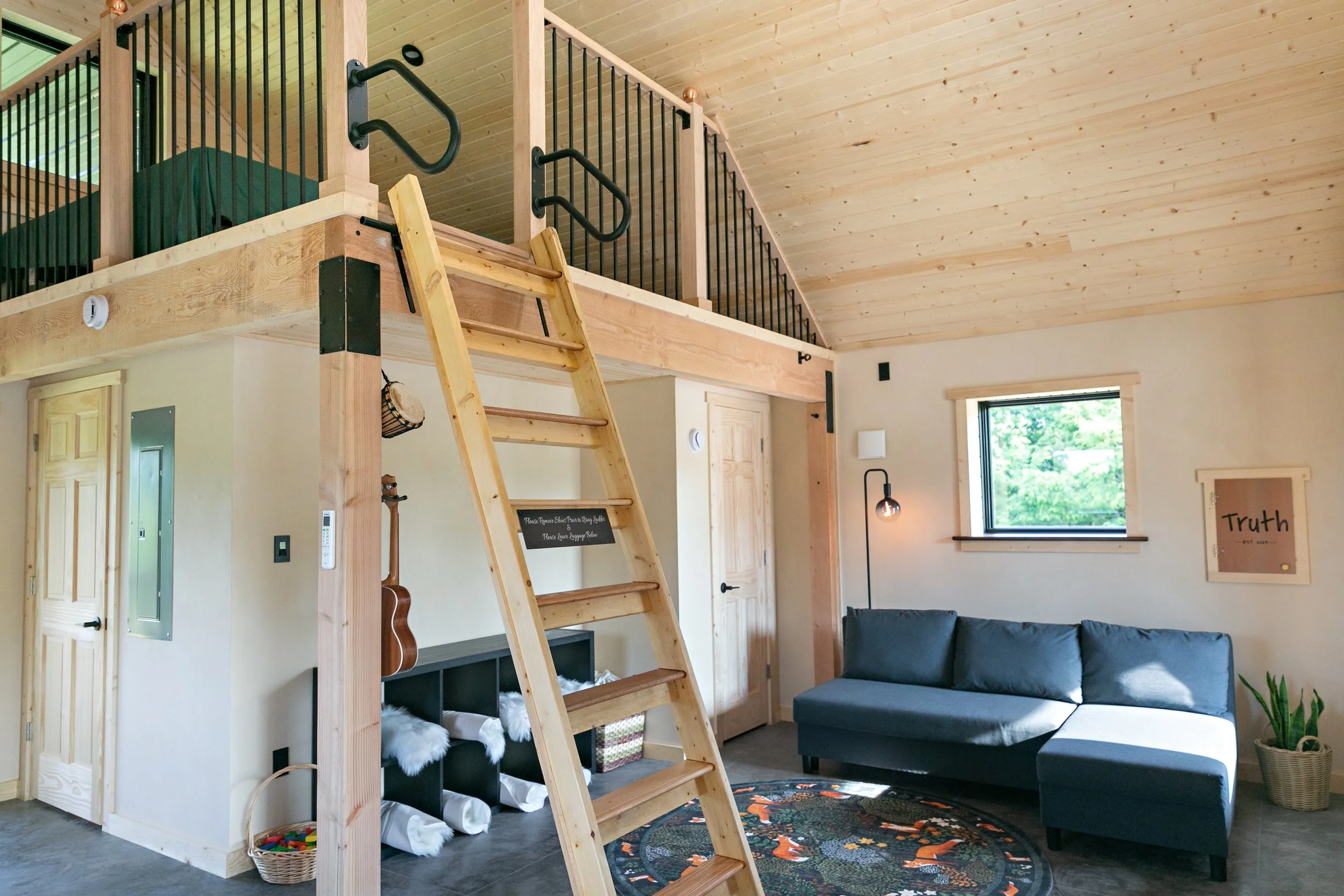 Warm and inviting natural straw panel home interior featuring smooth plaster walls and open living space beneath a loft — built by Building Integrity