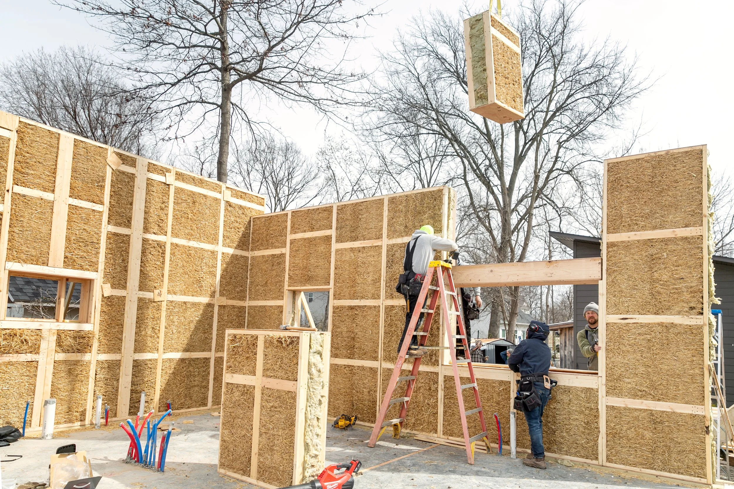 Building Integrity team installing prefabricated straw panels with a boom truck crane on a job site