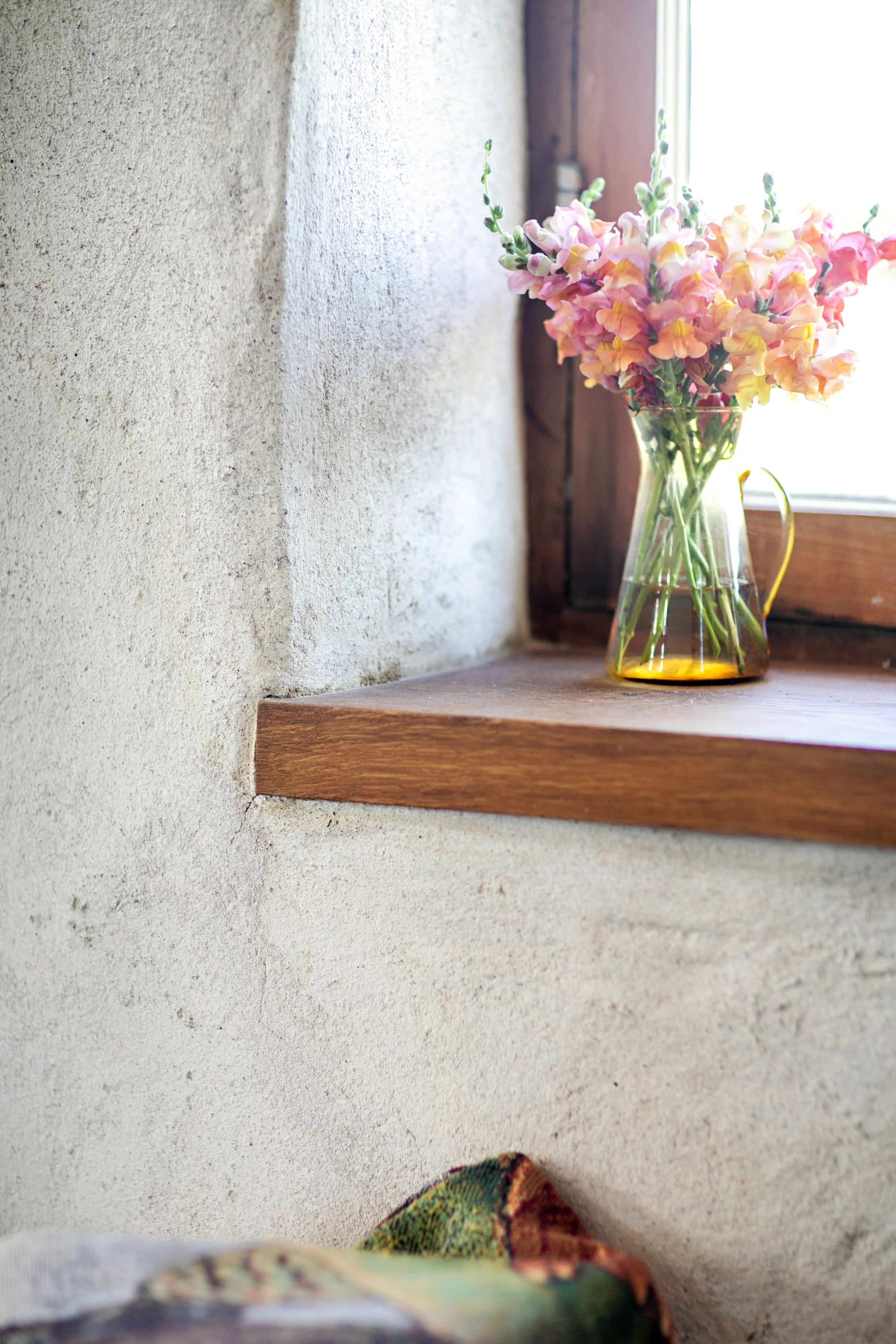 Thick natural plaster walls and deep window sill detail showcasing the aesthetic and thermal benefits of Building Integrity's straw panel construction