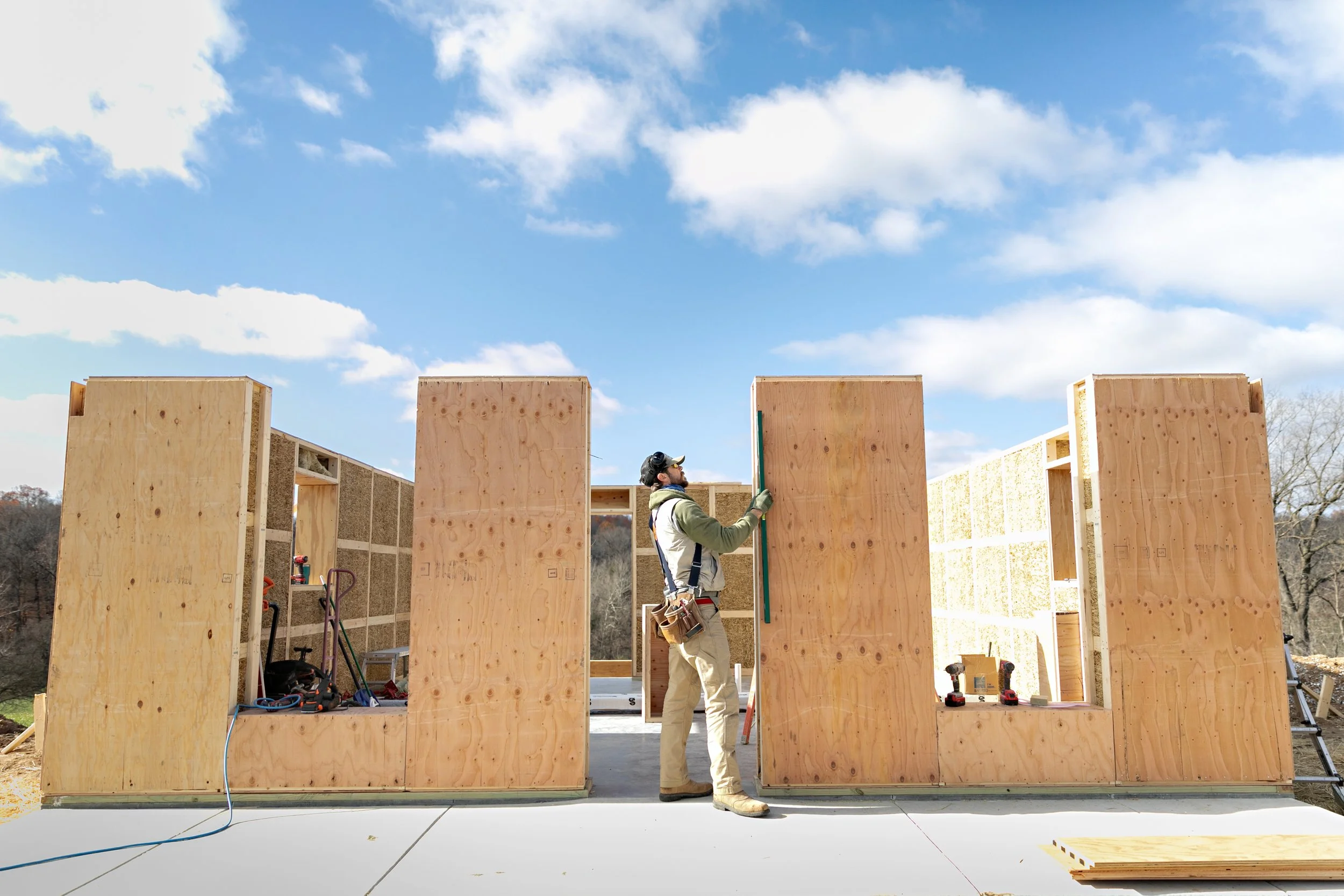 Building Integrity founder Adam using a level on a prefabricated straw panel during construction