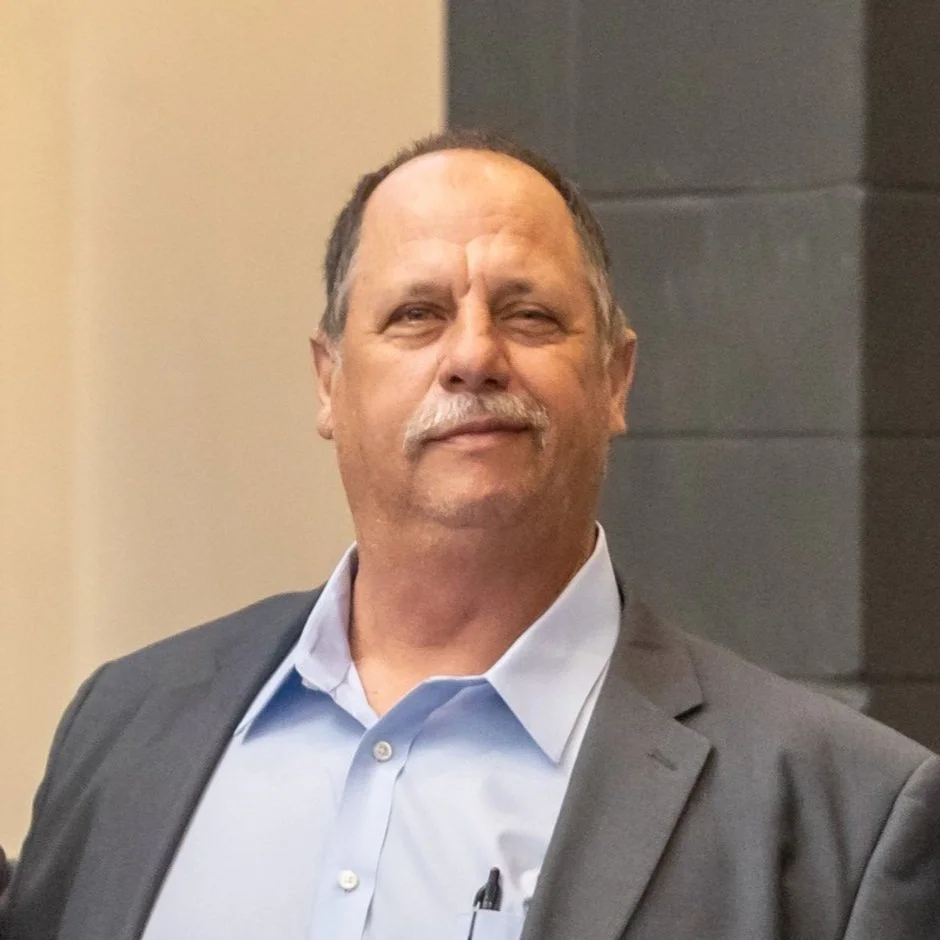 Timmy Lambe in business attire, standing indoors with a neutral expression.