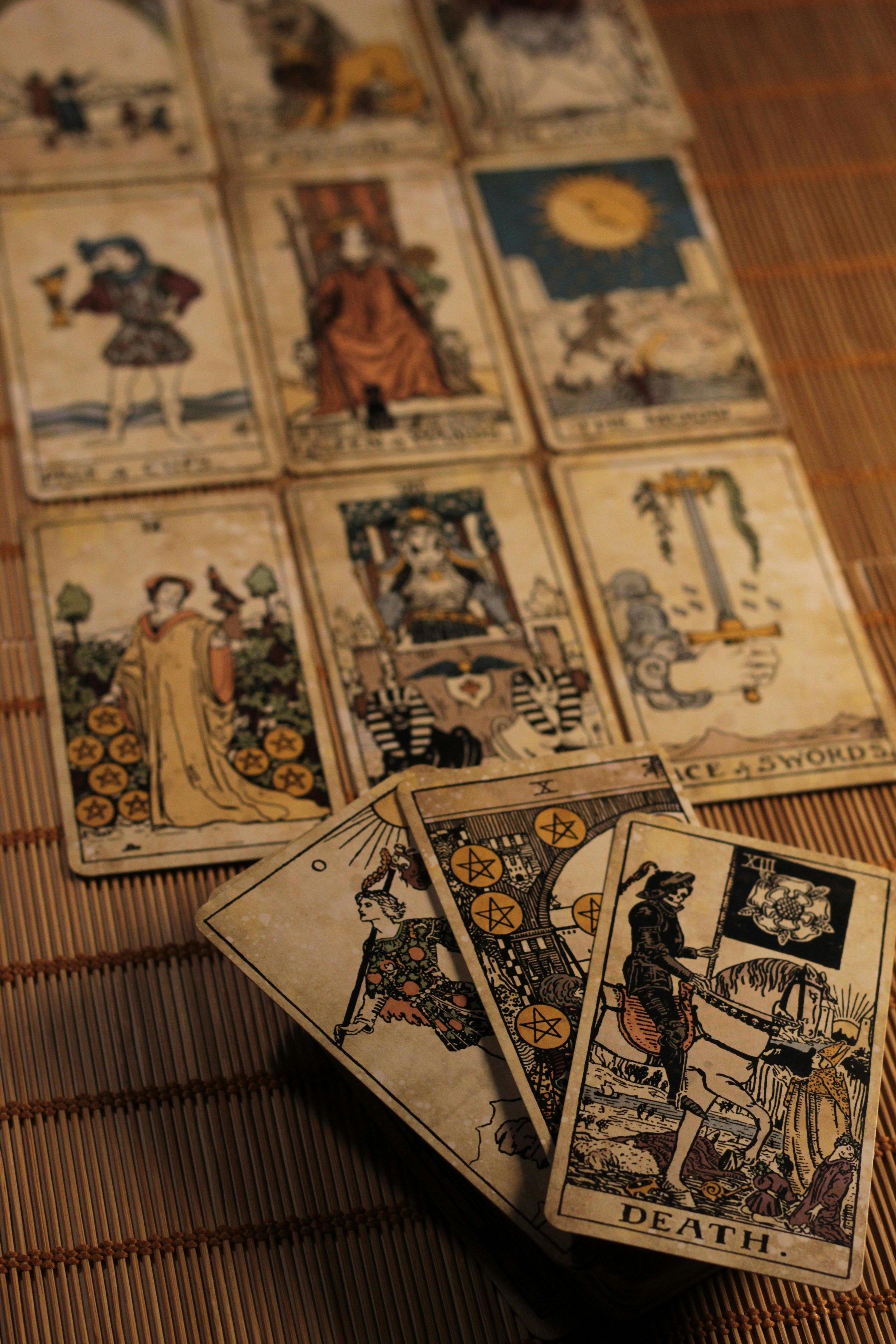 A spread of vintage Tarot cards, including The High Priestess, Death, and other Major Arcana cards, laid out on a wooden surface.