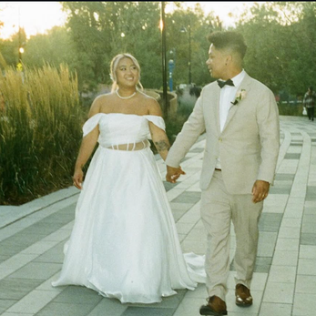 Scenic landscape of a mountain range with a lake and rolling grassy hills in the foreground, under a cloudy sky.