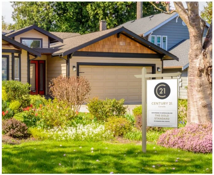 Front of a suburban house with a well-maintained garden and a for sale sign from Century 21.