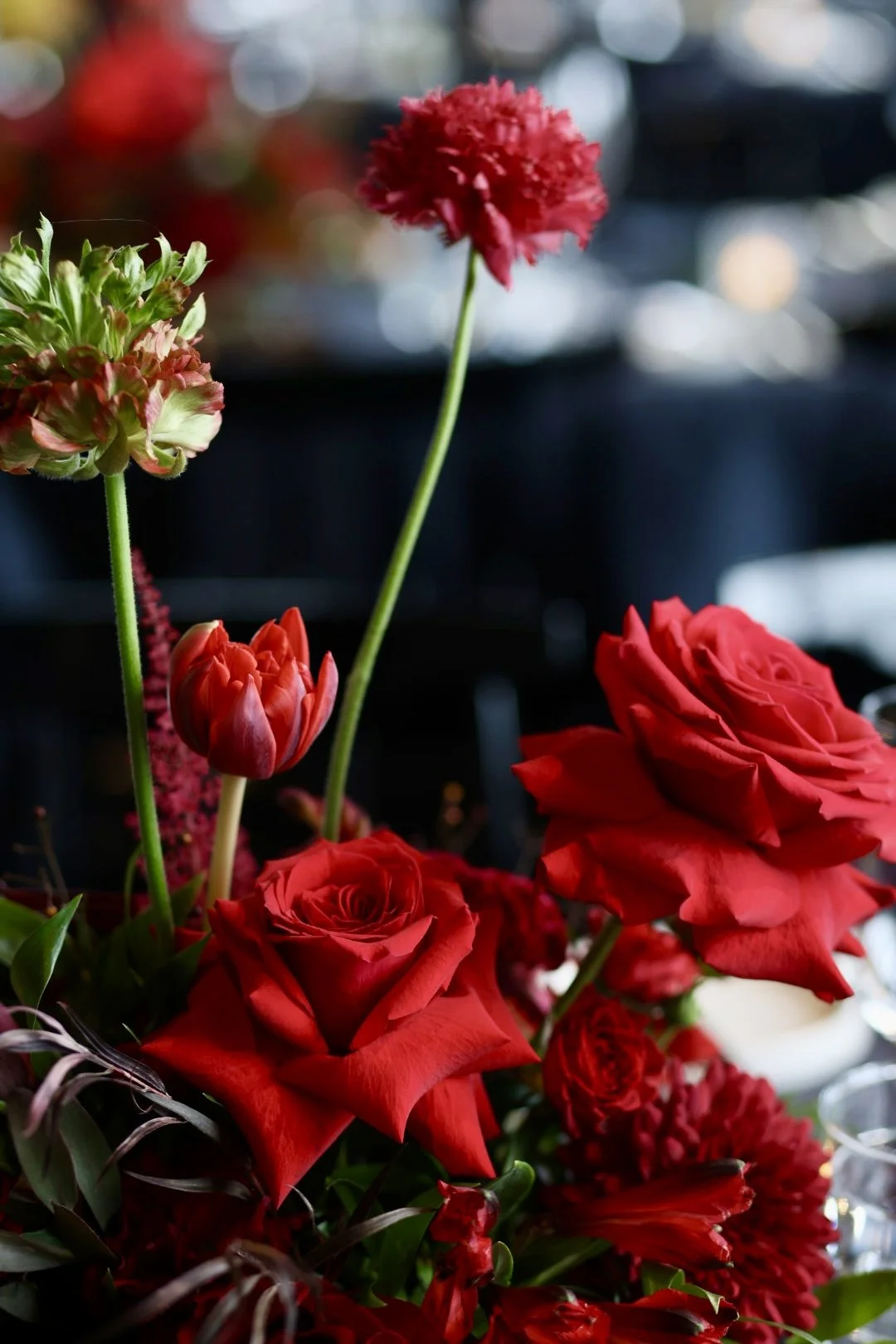 An ikebana style floral arrangement centerpiece of roses on a table in an elegant special event venue. 
