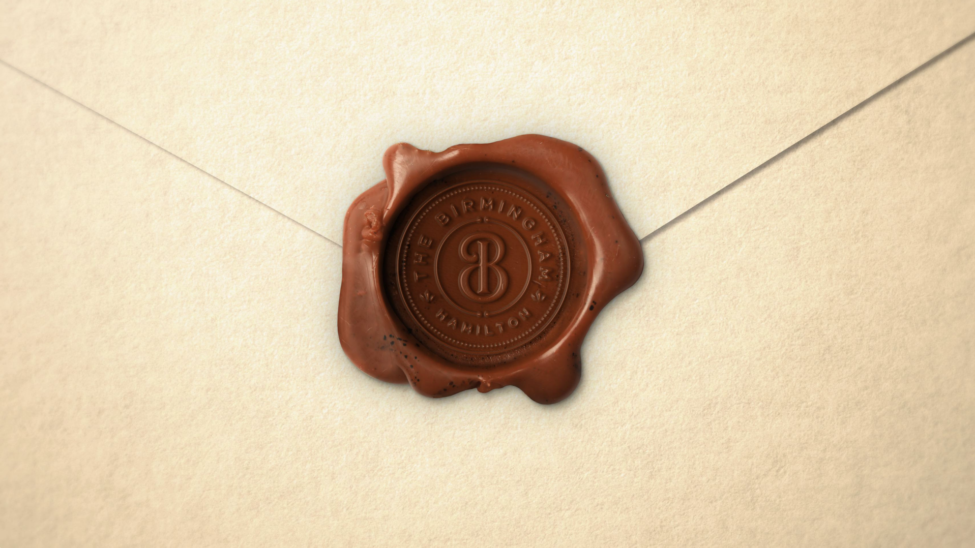 Cream-colored envelope sealed with a brown wax seal embossed with the words 'The Birmingham Hamilton' and a decorative monogram 'B'.