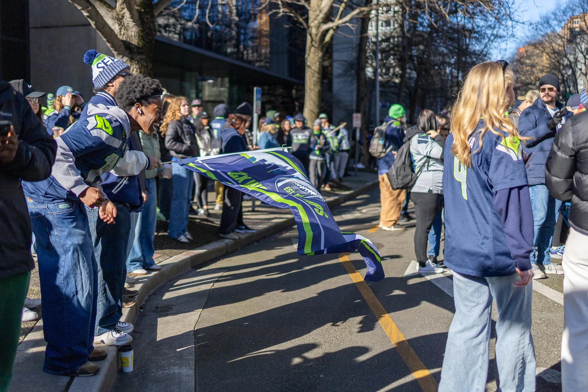 Fans line up along the side of a street to watch the Seahawks Super Bowl LX victory parade.