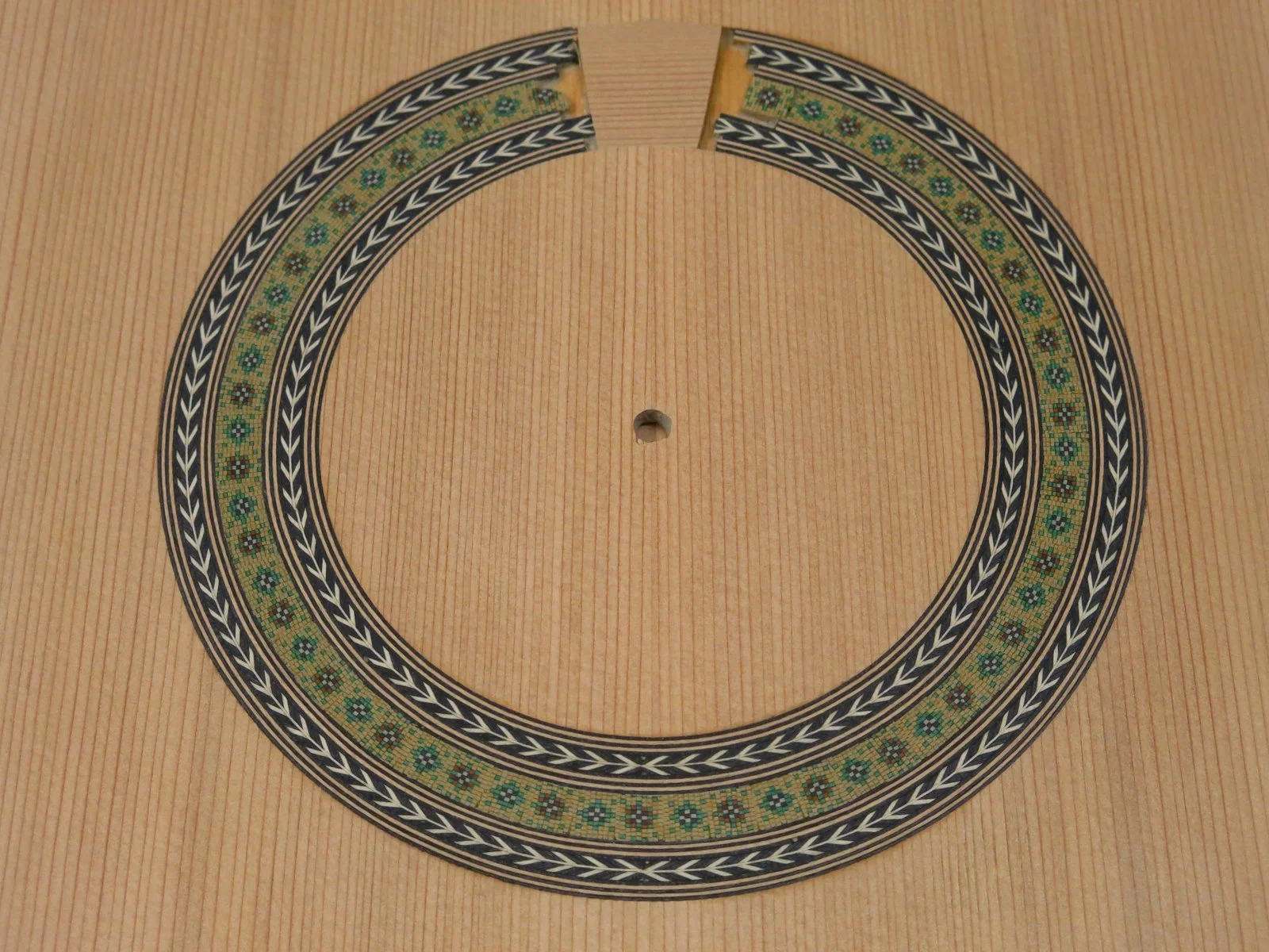 Decorative circular pattern on a wooden surface, with a small hole in the center.